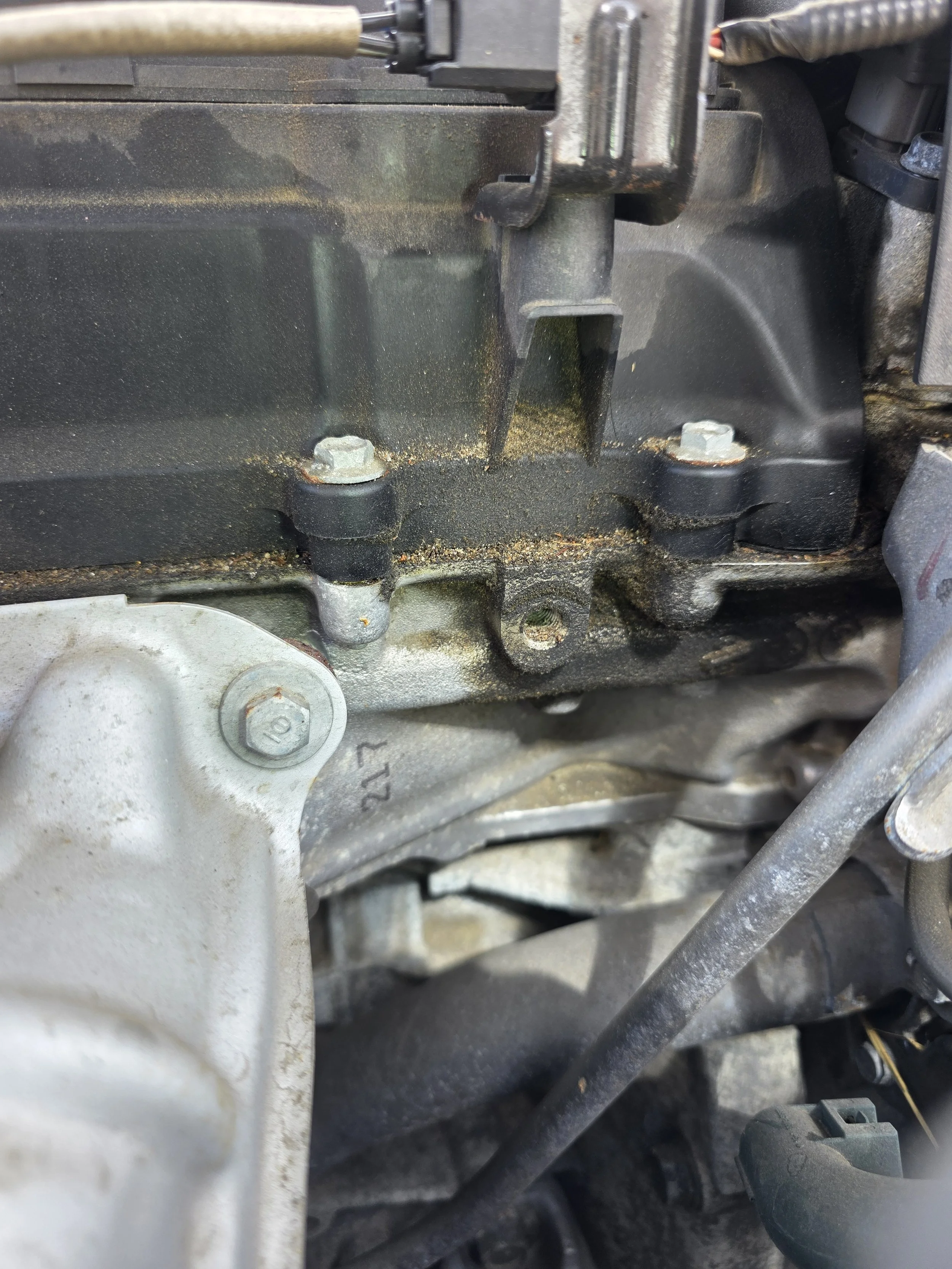 Close-up of an engine with visible bolts, metal parts, and some dirt or grime.