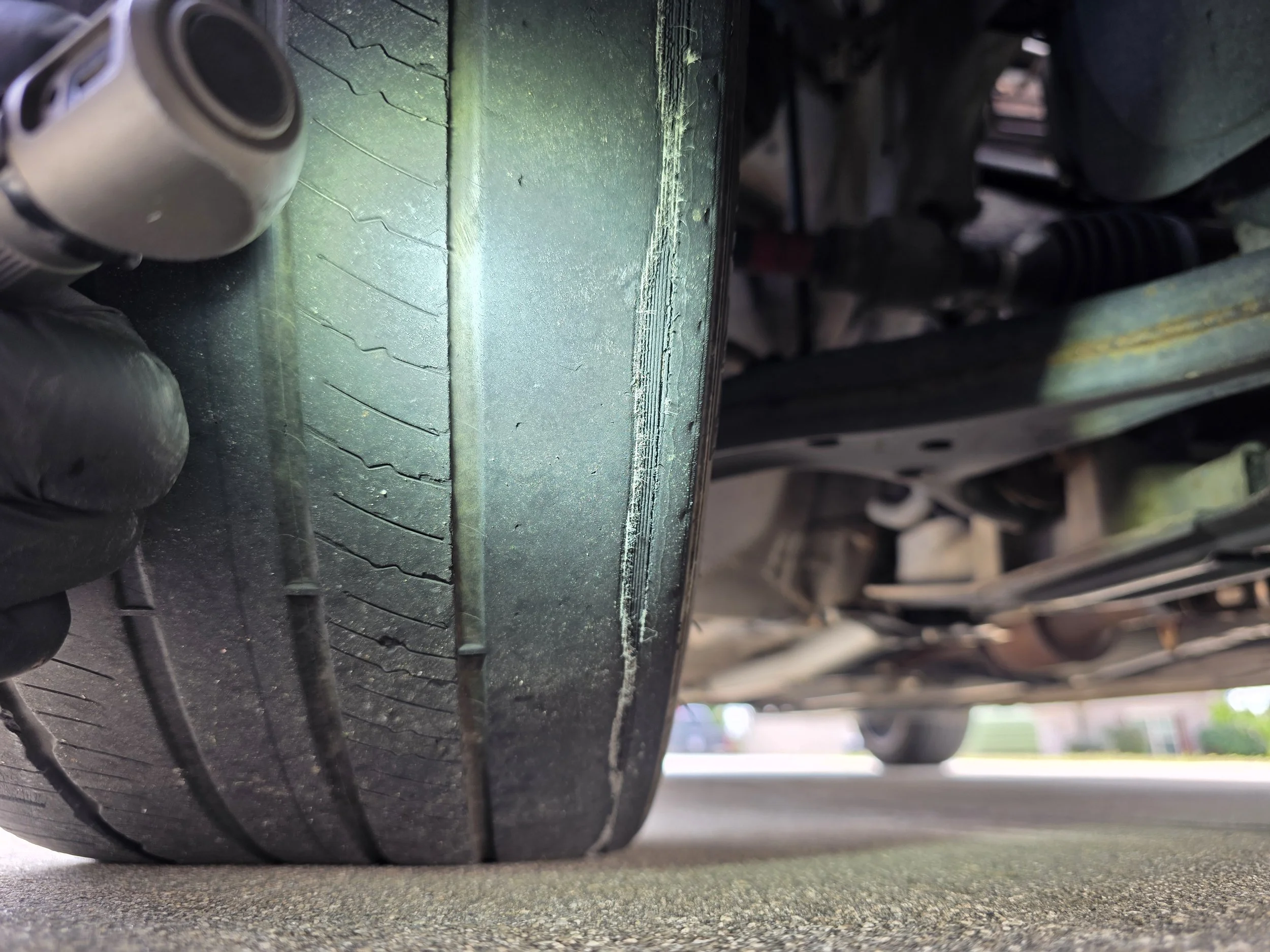 Underside of a vehicle showing a worn tire and part of the suspension system.