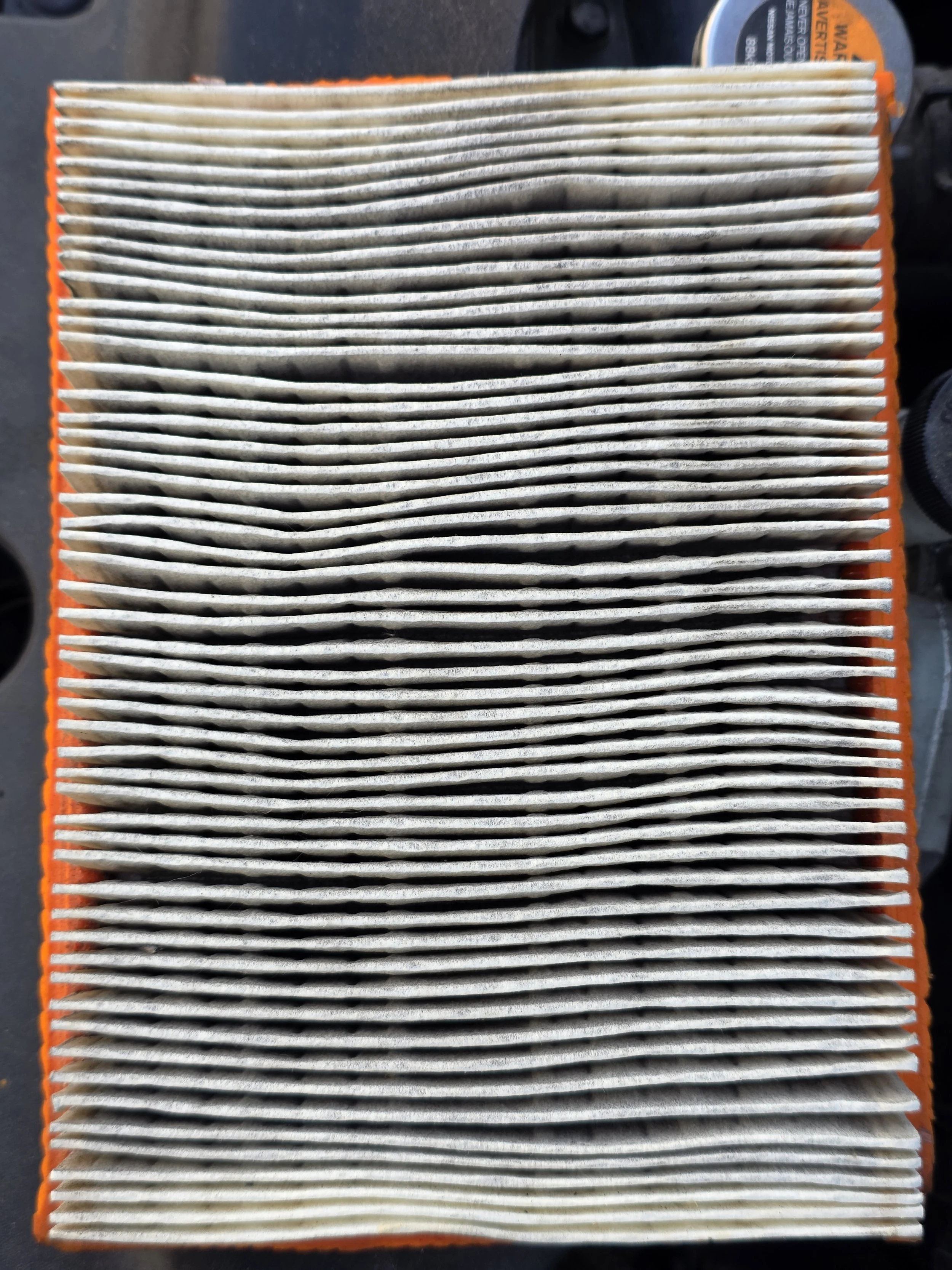 Close-up of a used automotive air filter with dirt and debris accumulated between pleats.