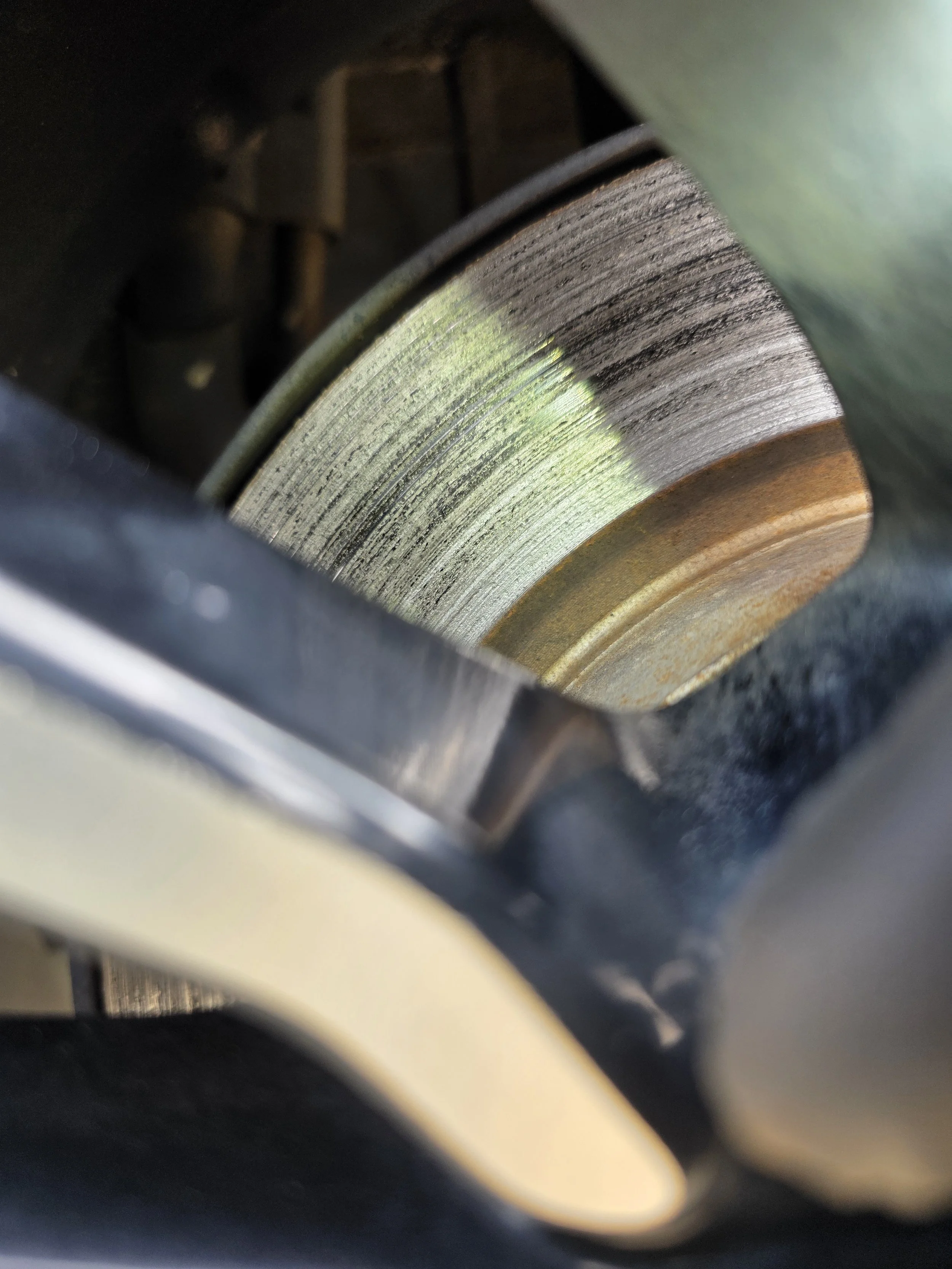 Close-up view of a brake rotor in a vehicle, showing surface wear and rust on the metal disc.