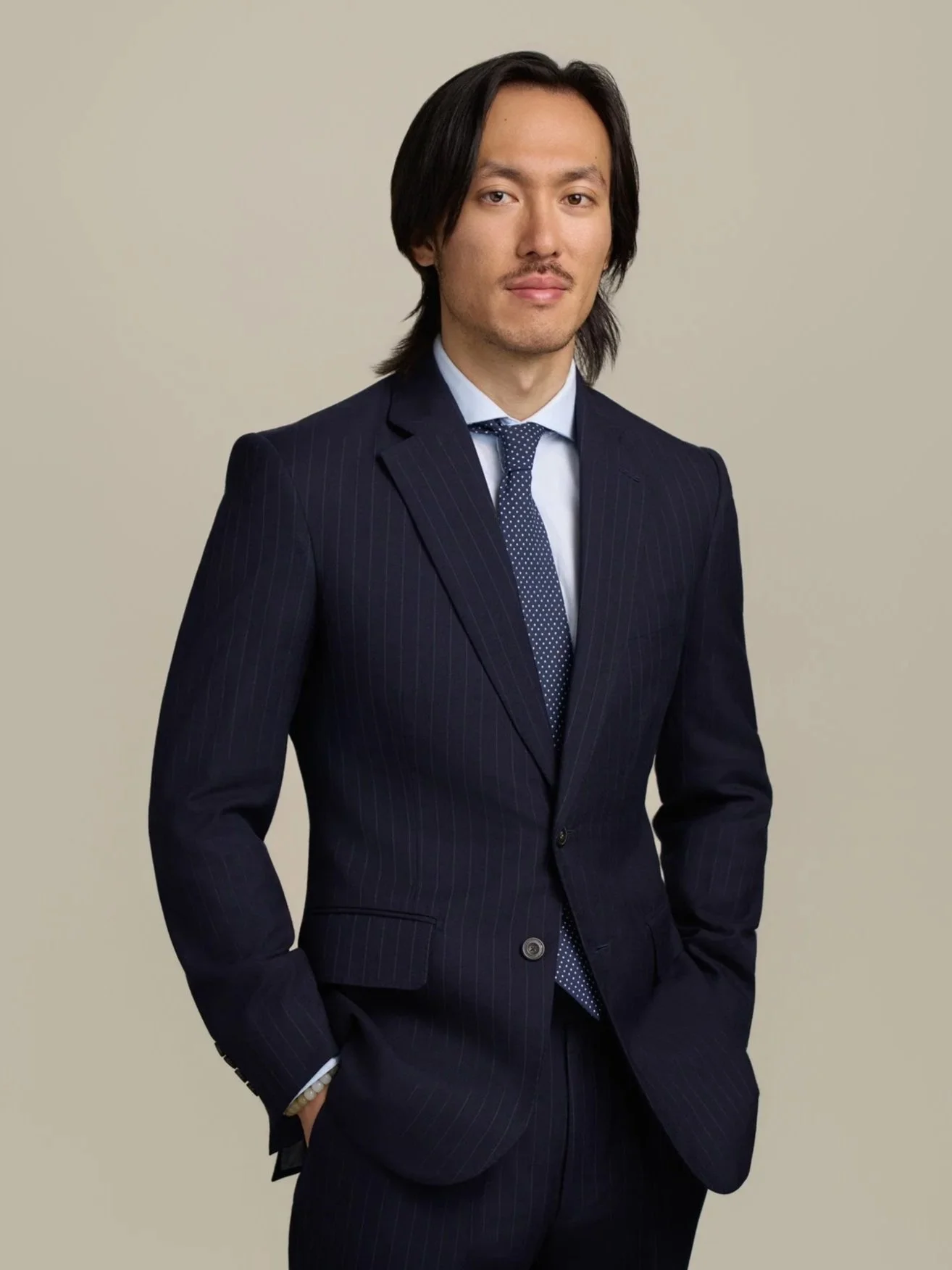 Executive headshot of a man in a pinstripe suit photographed in New York City against a neutral studio background