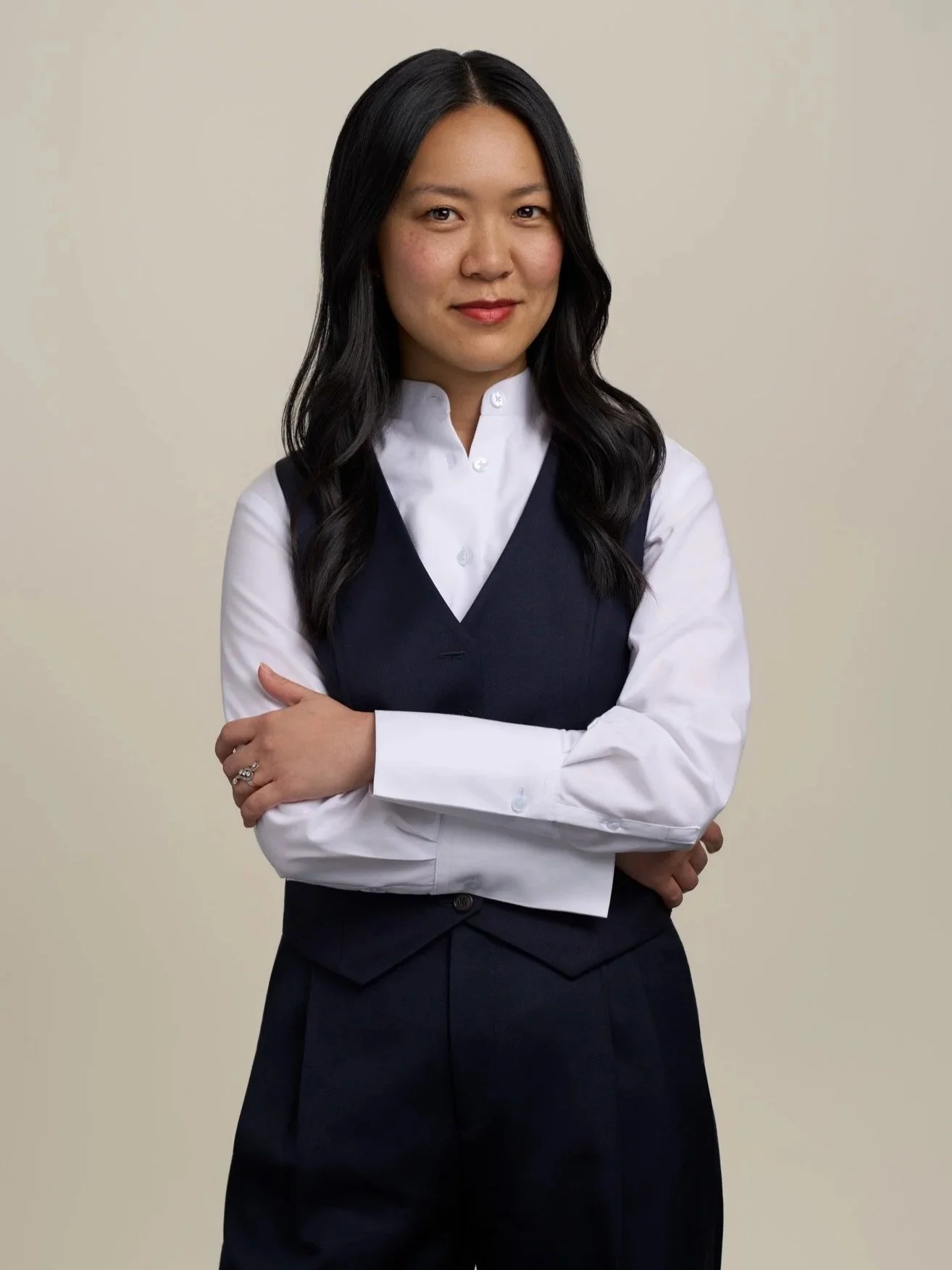 Studio portrait of a woman in business attire standing with arms crossed against a neutral background in a New York City headshot session