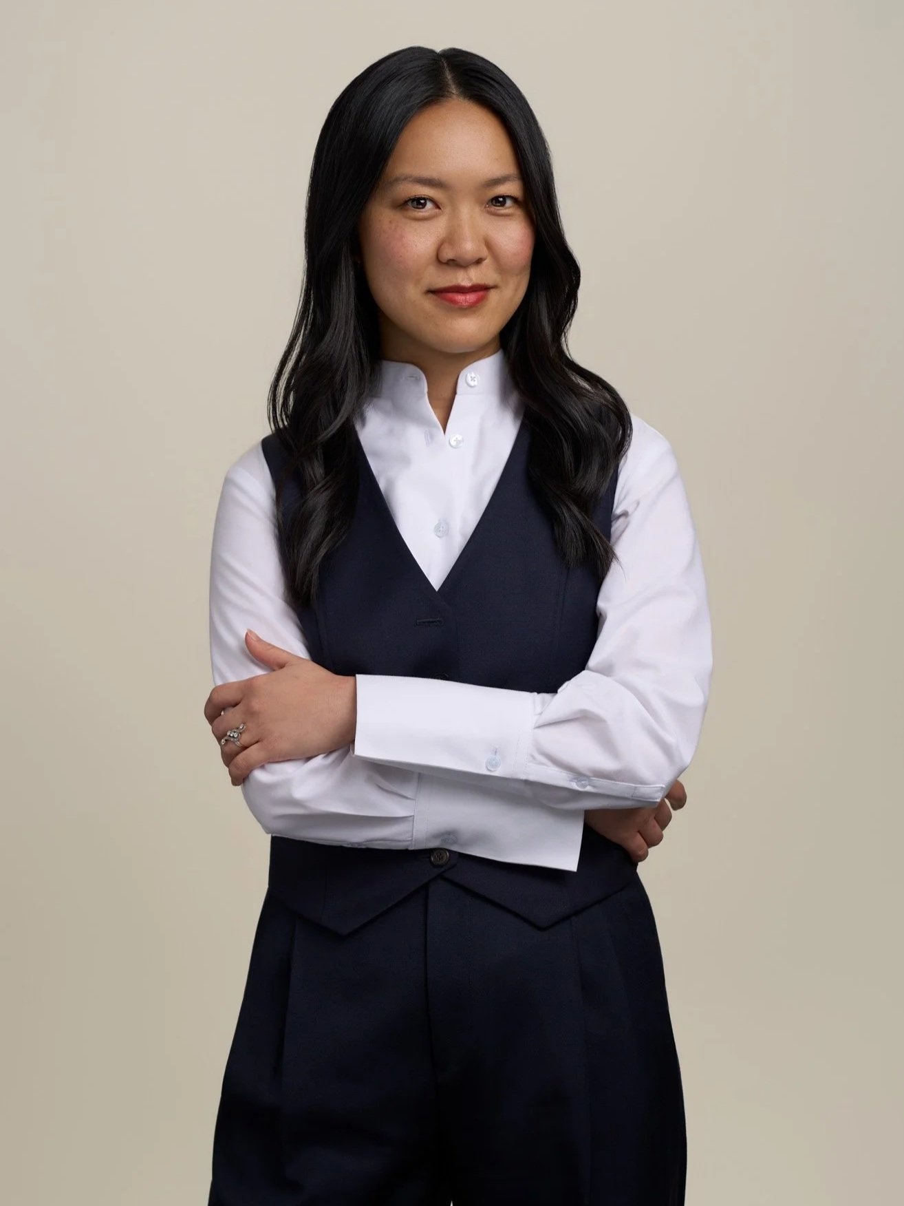 Studio portrait of a woman in business attire standing with arms crossed against a neutral background in a New York City headshot session