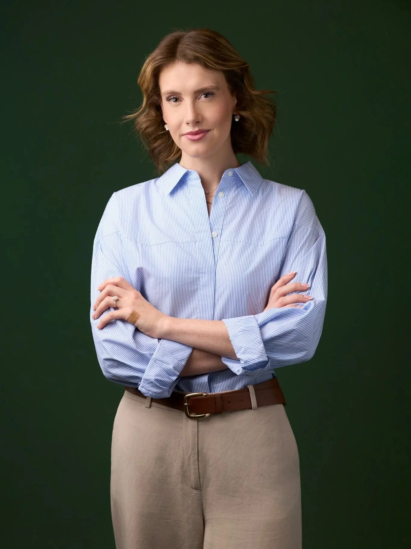 Modern corporate headshot of a woman photographed in New York City, standing against a dark green studio backdrop