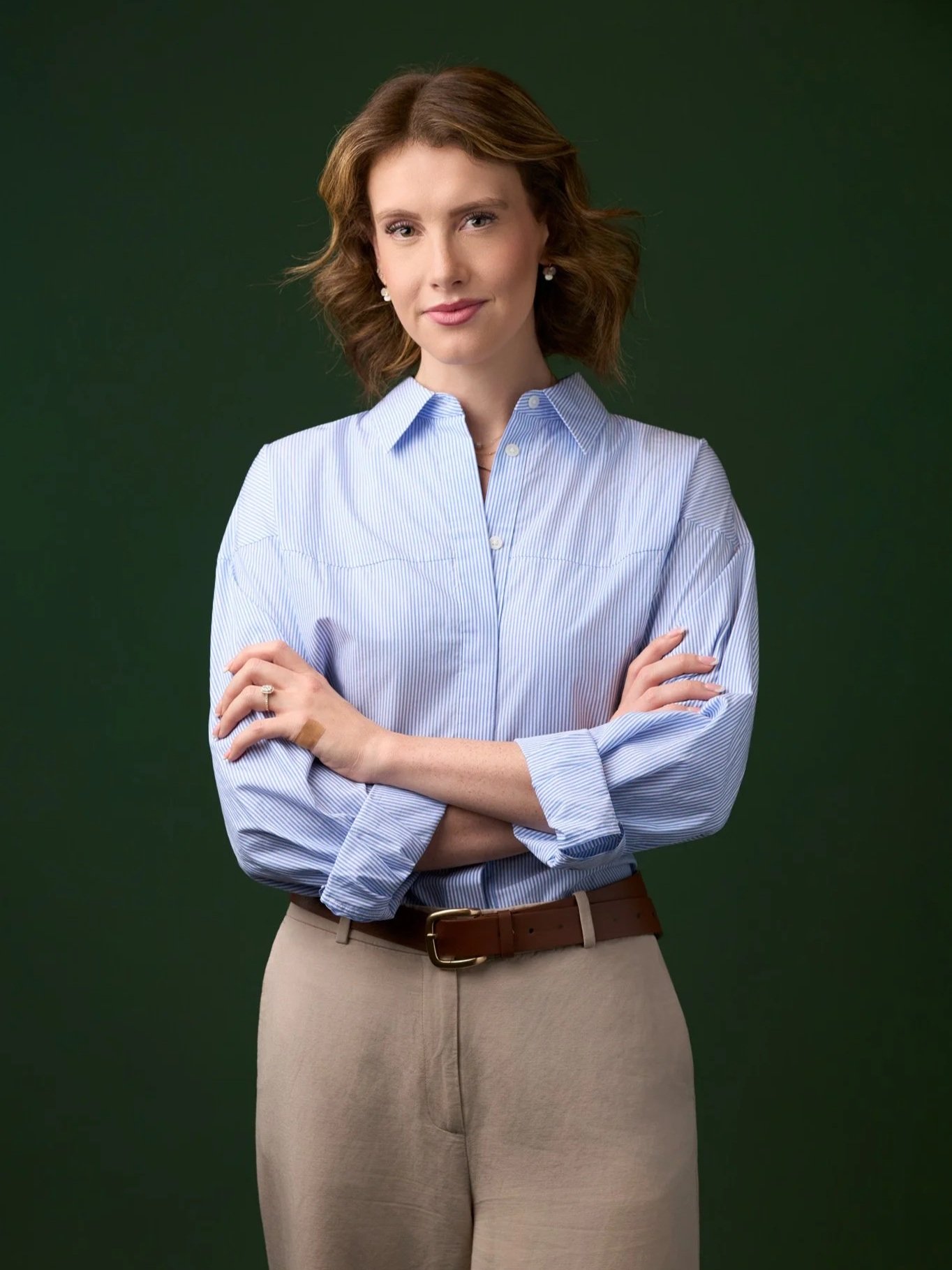 Modern corporate headshot of a woman photographed in New York City, standing against a dark green studio backdrop