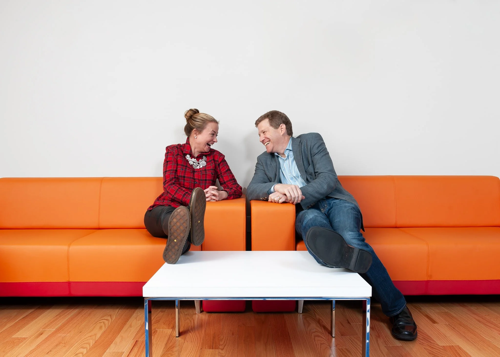 Corporate lifestyle photograph of two colleagues laughing together in a New York City office lounge