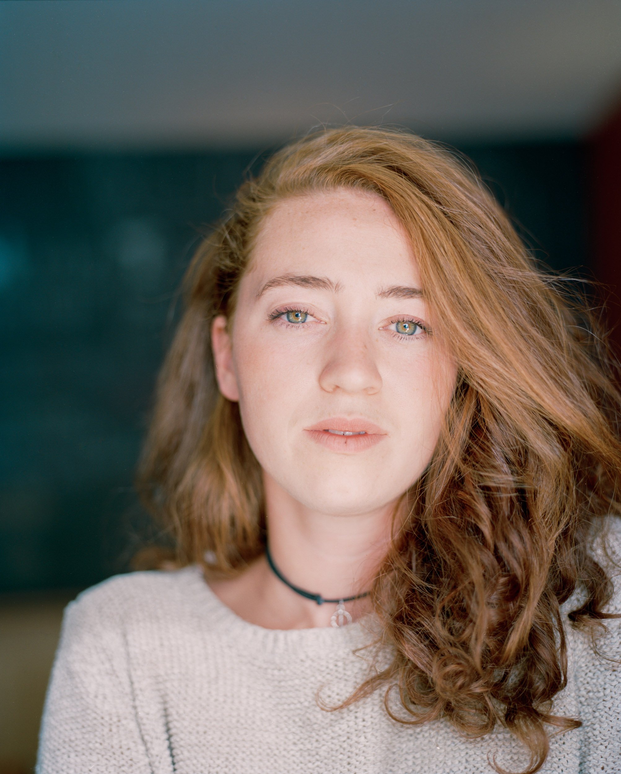 Natural light headshot of a woman with soft background blur, clean modern portrait with shallow depth of field and direct eye contact.