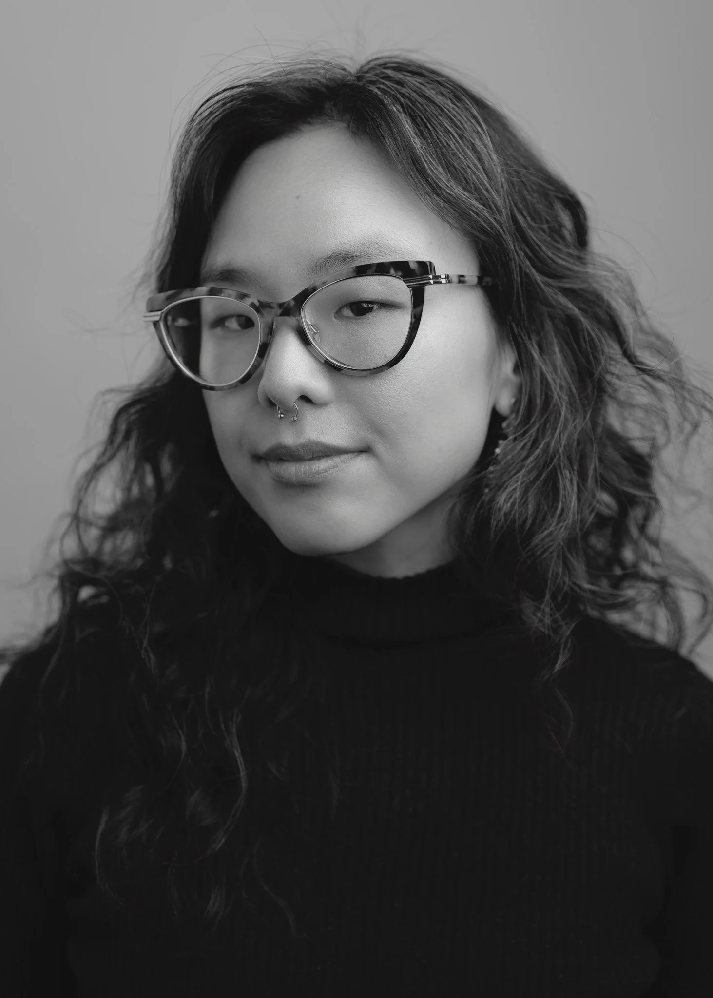 Black and white actor headshot of a woman with glasses and wavy hair, soft directional lighting and shallow depth of field, photographed in New York City by David Pexton.