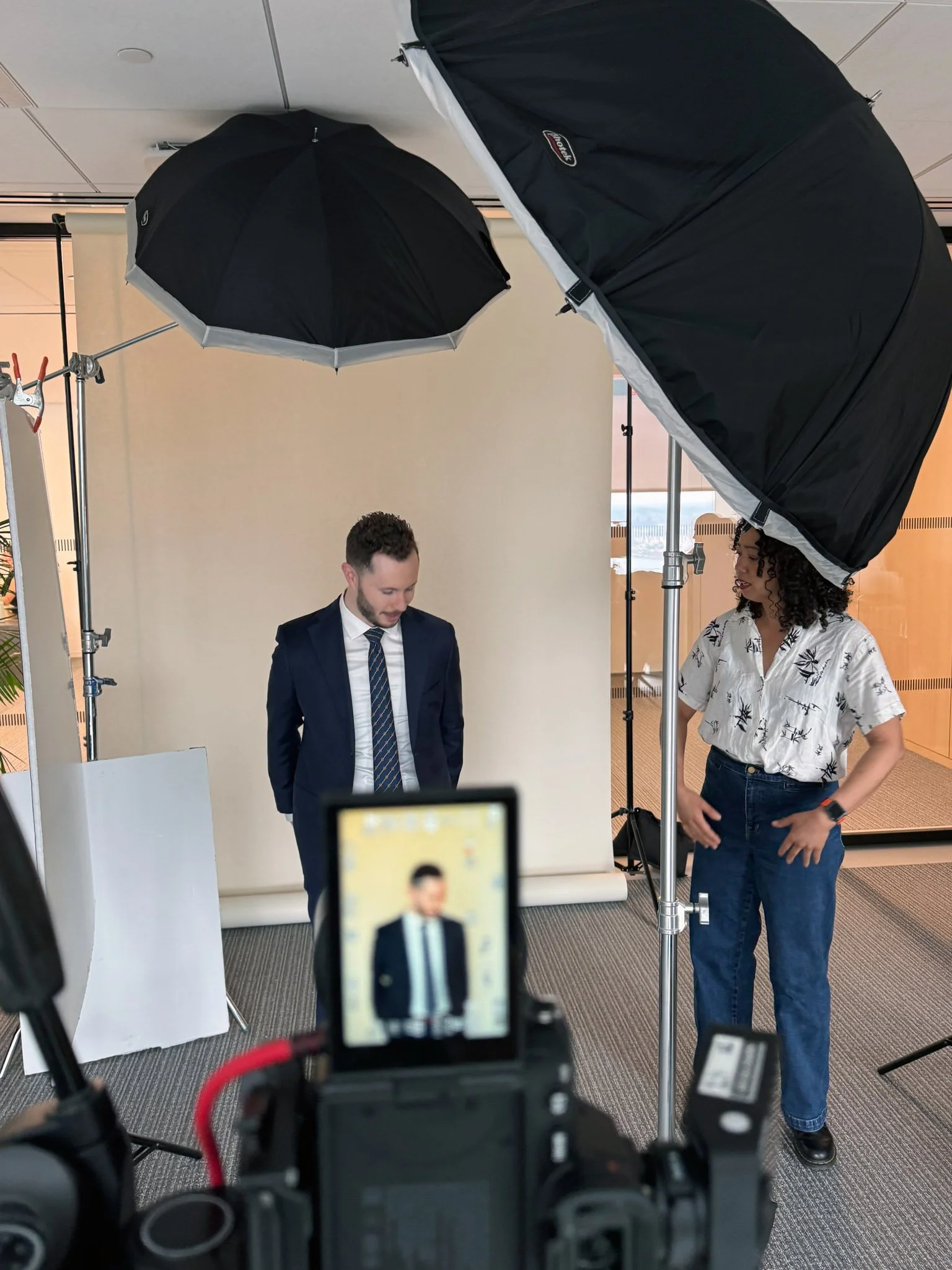 Christine directing a subject during an on-location corporate headshot session in a Manhattan office, with lighting setup visible