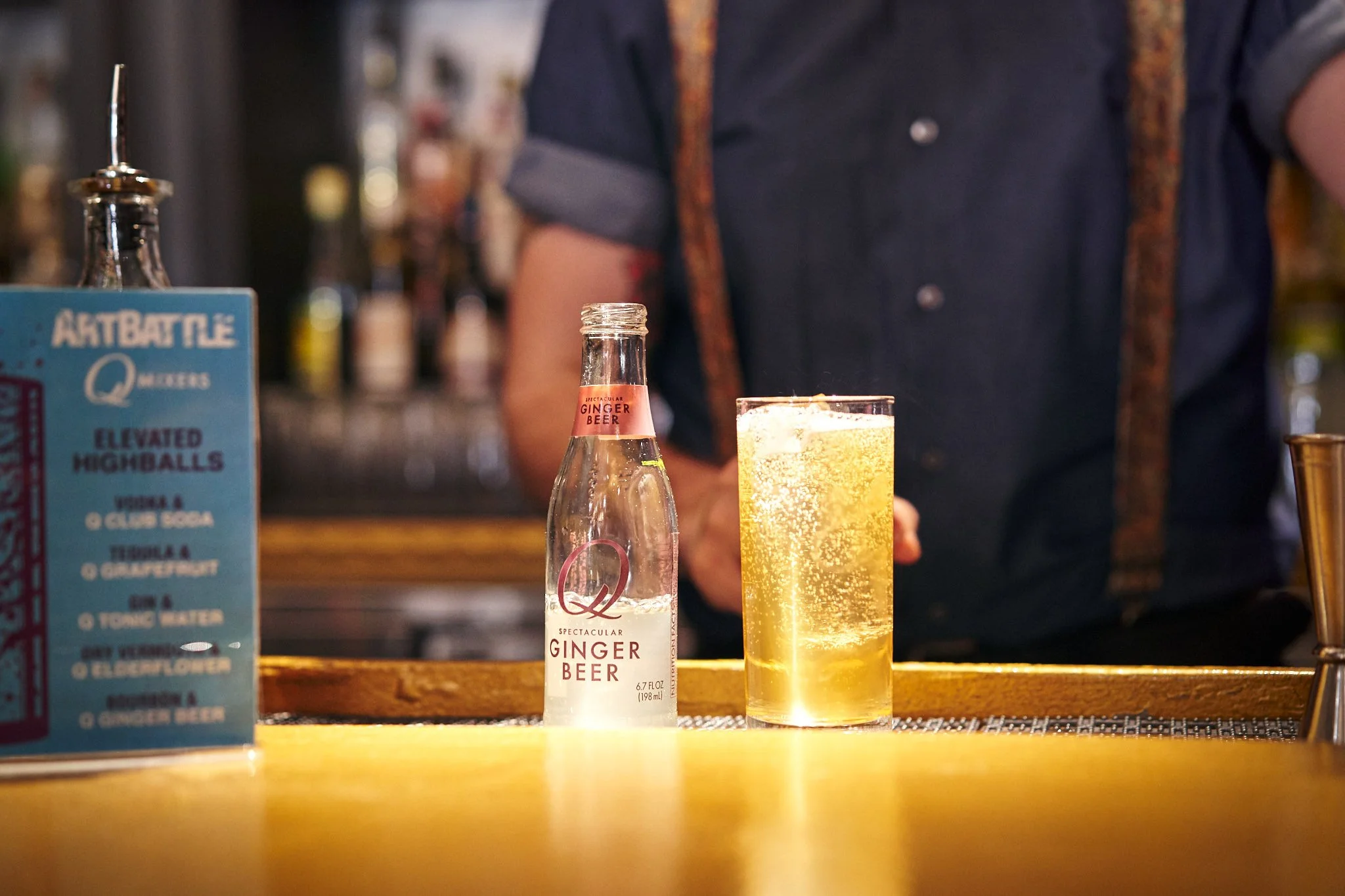 Commercial beverage photography featuring a cocktail and soda bottle on a bar counter, captured in warm light for lifestyle and hospitality marketing use.