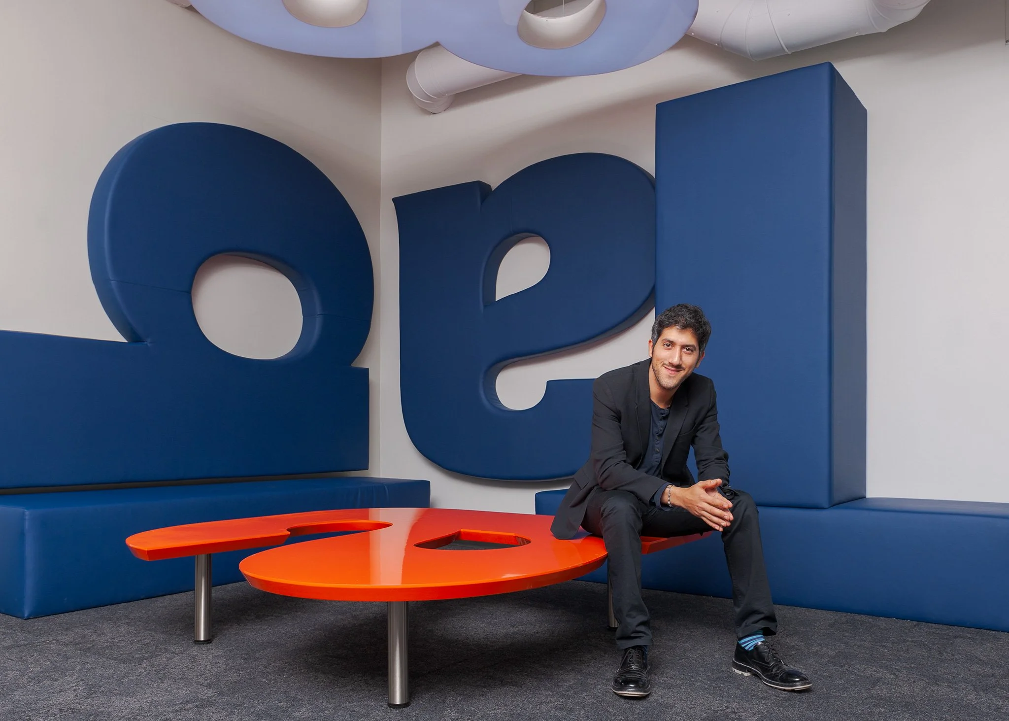 Corporate lifestyle portrait of CEO, Adam Singolda seated in a modern office space with bold architectural branding in New York City