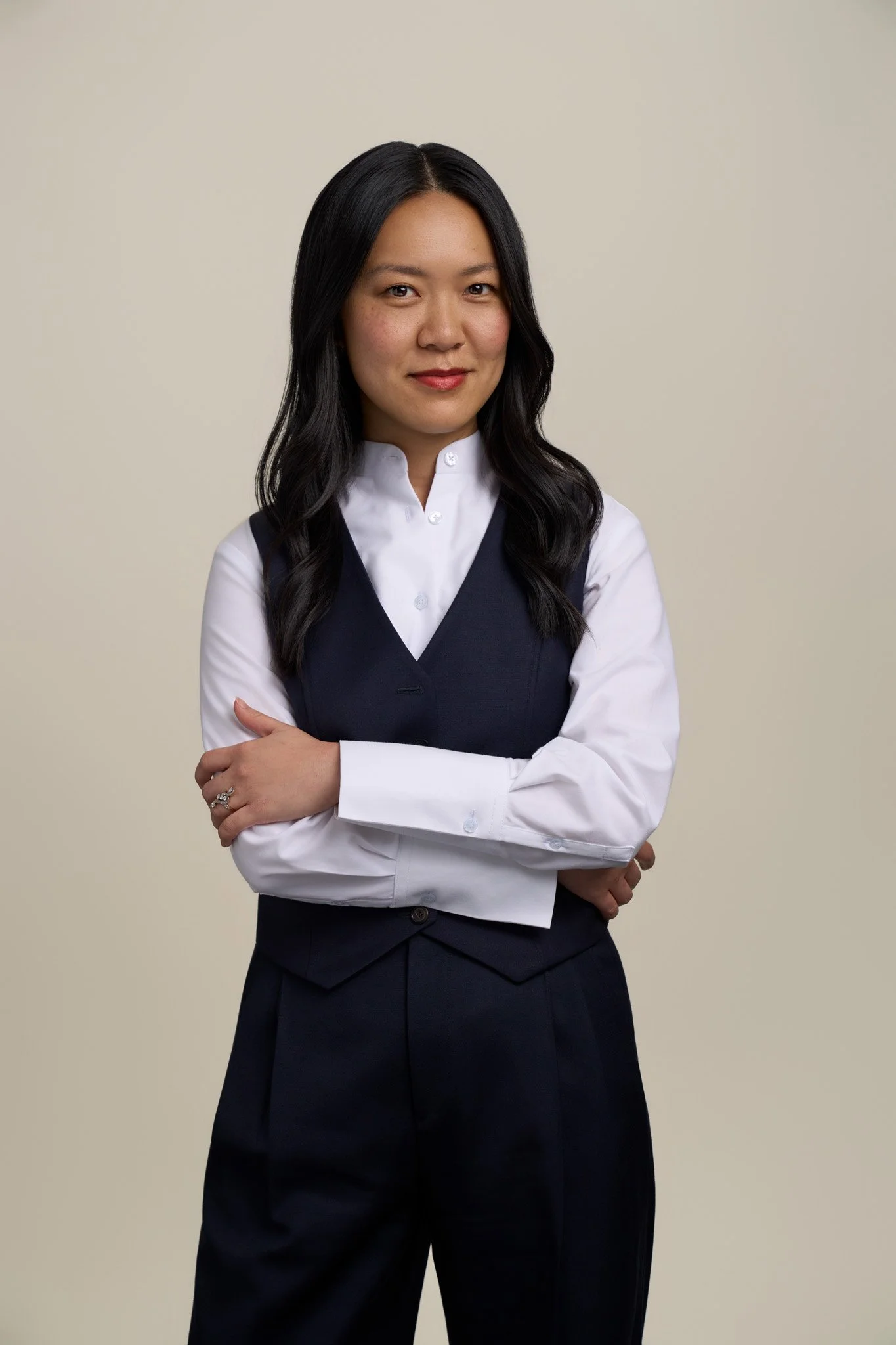 Female professional in a crisp white shirt and black vest with arms crossed, corporate studio headshot photographed in New York City