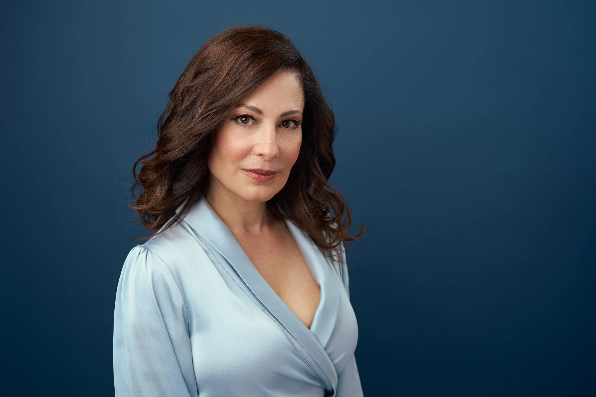 Actor headshot of Lisa Gorlitsky against a blue studio background, soft flattering lighting and confident expression, photographed in New York City by David Pexton.