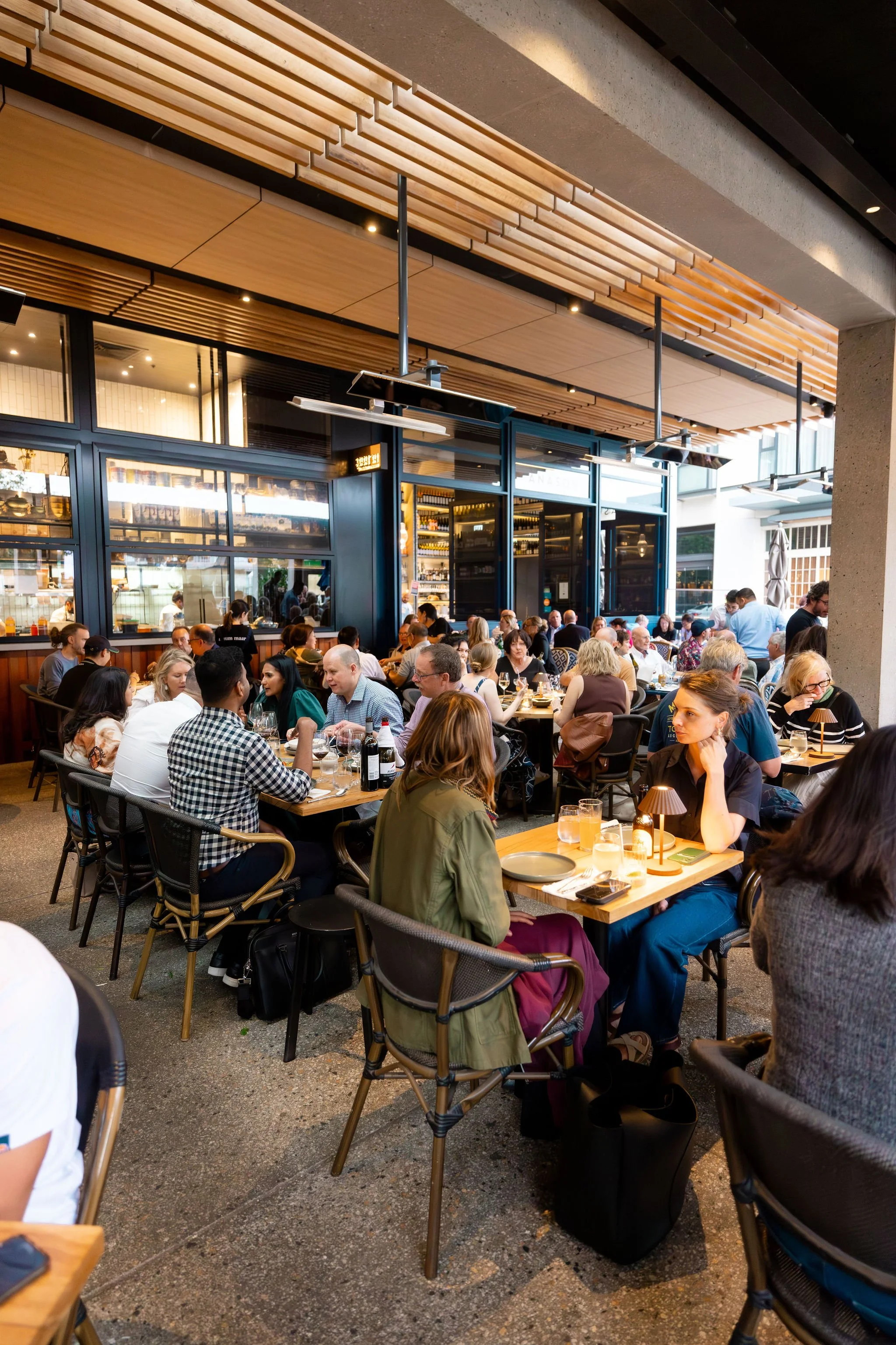 Photo of a lively dining scene at Muum Maam, with guests enjoying food and drinks in a warm, vibrant restaurant setting.