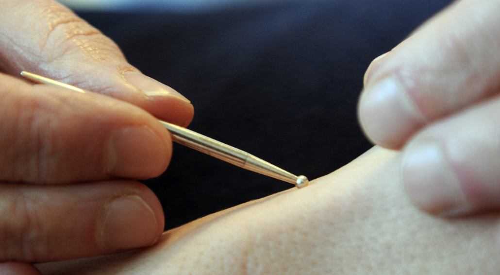 Hand holding metal tool near skin