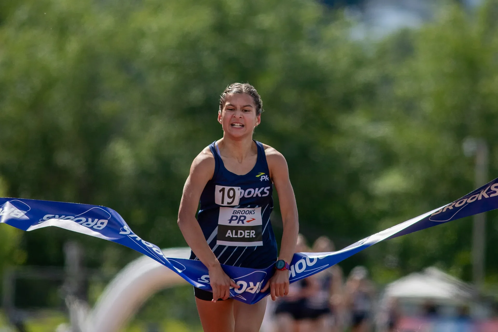 Junior distance star Angelina Alder aggressively breaking the tape to win the Girls Junior Mile and establish a new 13-year-old world record time of 4:38.25.