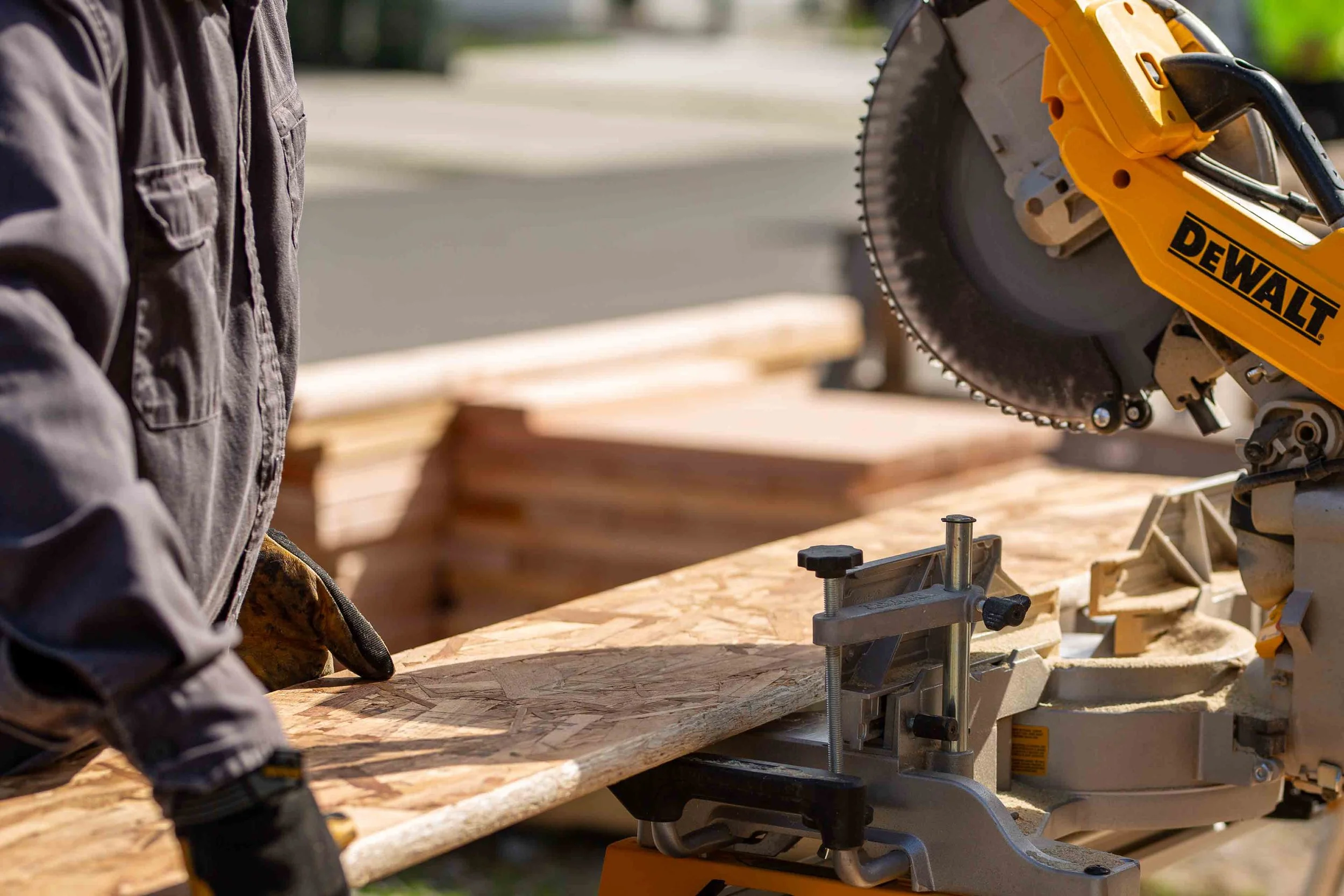 Volunteer cutting framing lumber with a DEWALT saw during a South Puget Sound Habitat for Humanity build day