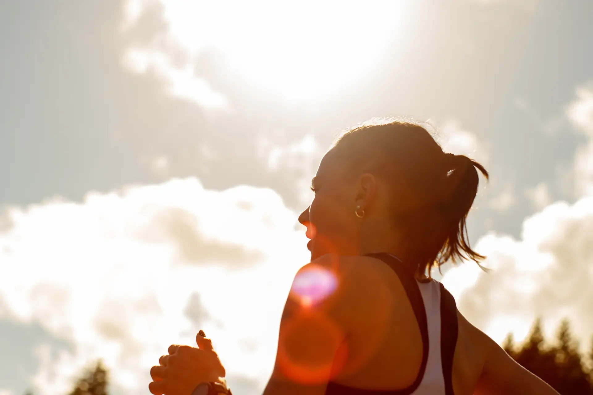 A backlit profile of athlete Leah Hennen running during the 3200m heat at Olympia High School, showing lens flare against a bright sky, photographed by Russell Moore.