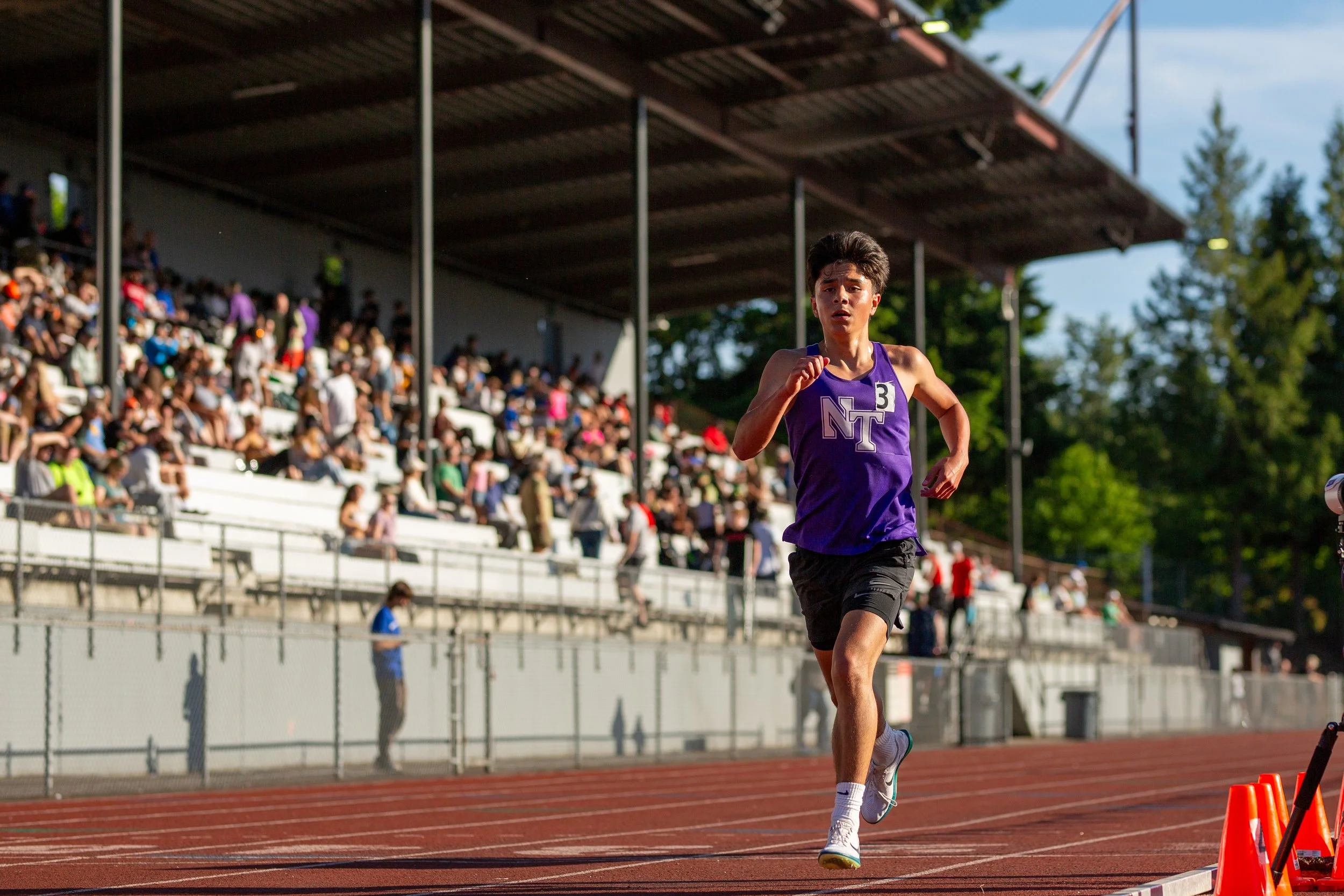 Sebastian Olson of Olympia High School running on the track at the 2026 District Championships in Kent, Washington, wearing a purple singlet.