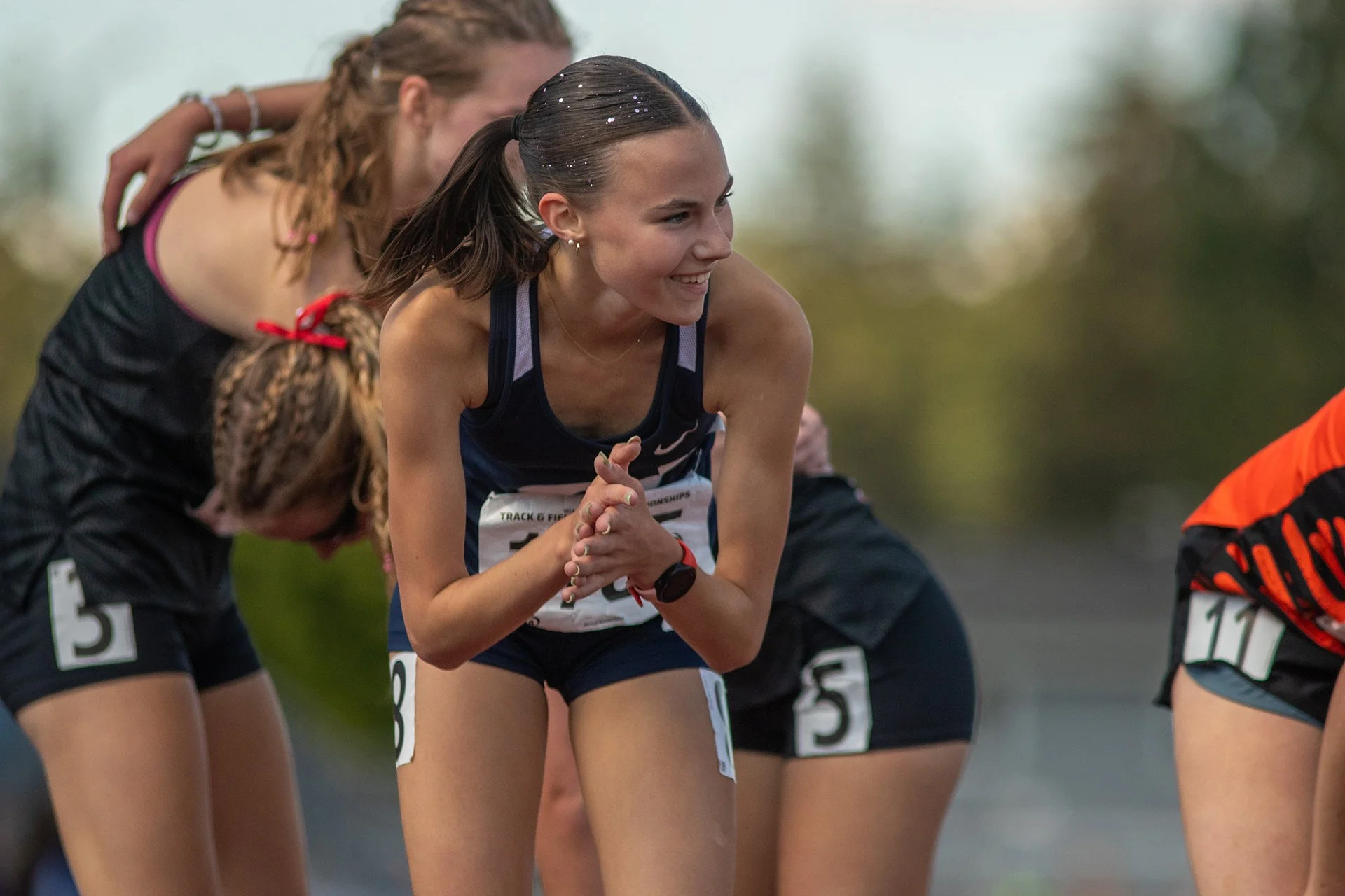 Leah Hennen of Olympia High School smiling and catching her breath after finishing the 3200m at the 2026 WIAA State Championships, surrounded by competitors
