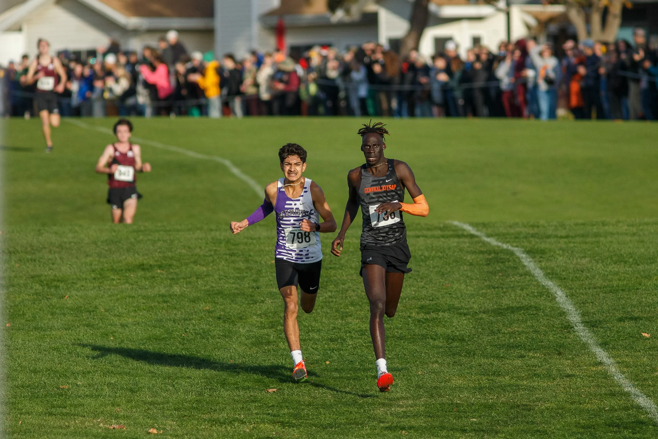 Two runners, Mana Voss and Leroy Mejia, sprinting side-by-side during the WIAA cross country championships.