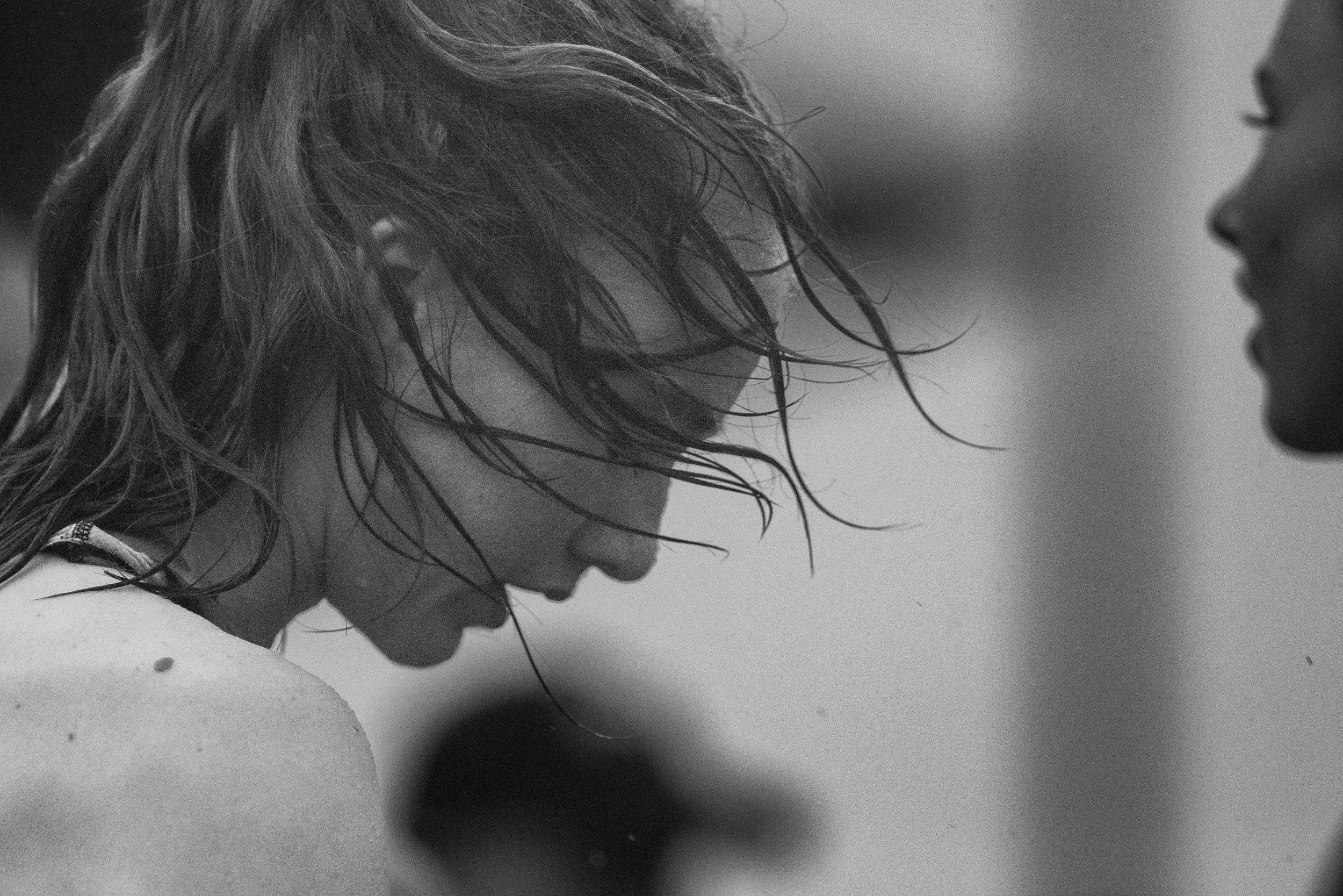 Moody black and white profile shot of Yelm High School runner Kailey Slevin, looking exhausted with her wet hair blowing wildly across her face in the wind.