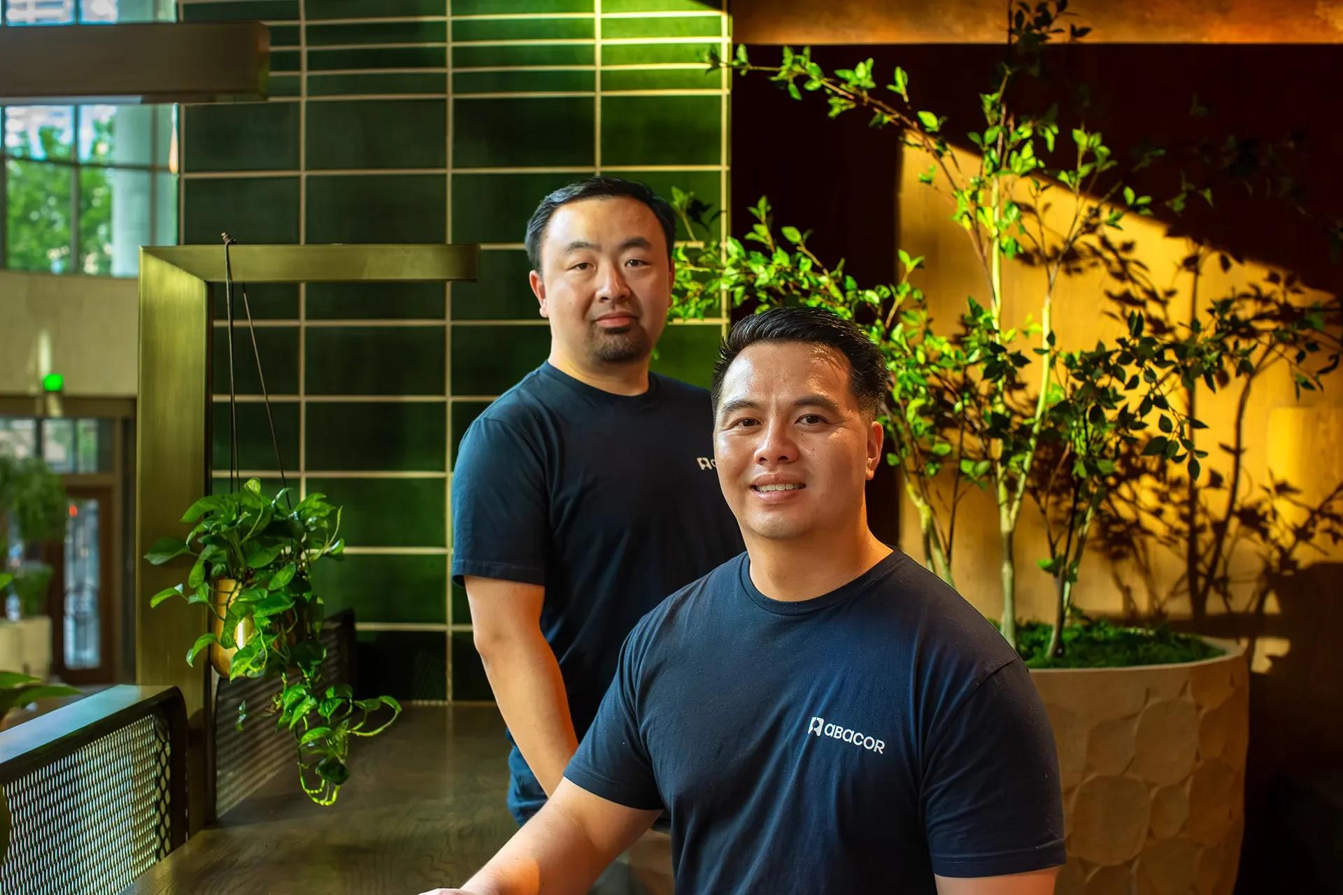 Two male Abacor AI founders smile during an office branding photoshoot.