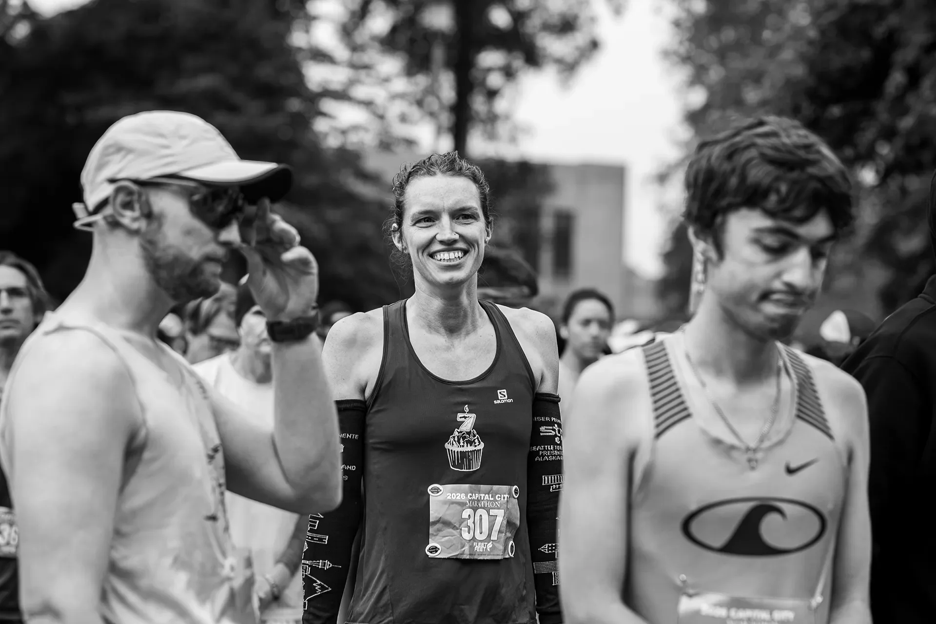 Black and white portrait of smiling female runner Jihan Grettenberger at the start line before winning the 2026 Capital City Marathon.