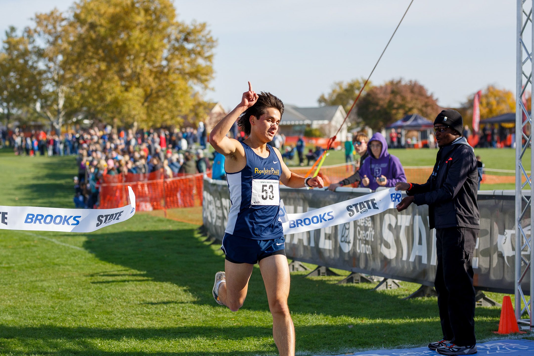 Kevin Hu crosses the finish line with arms raised in victory at the WIAA state cross country meet.