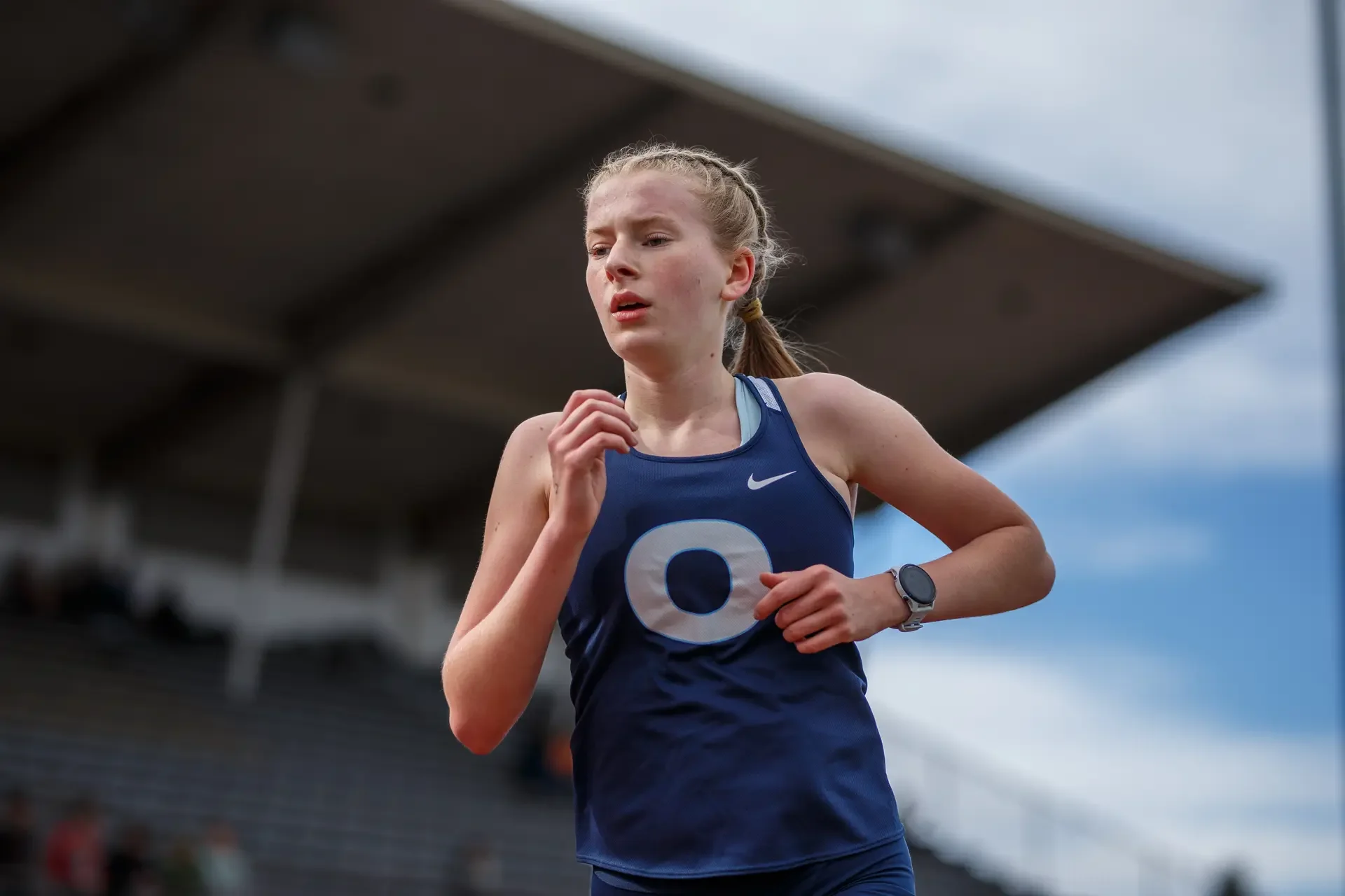 Caitlin Lanese of Olympia High School running at the 2025 Bear Relays at Ingersoll Stadium, wearing a navy Olympia singlet.