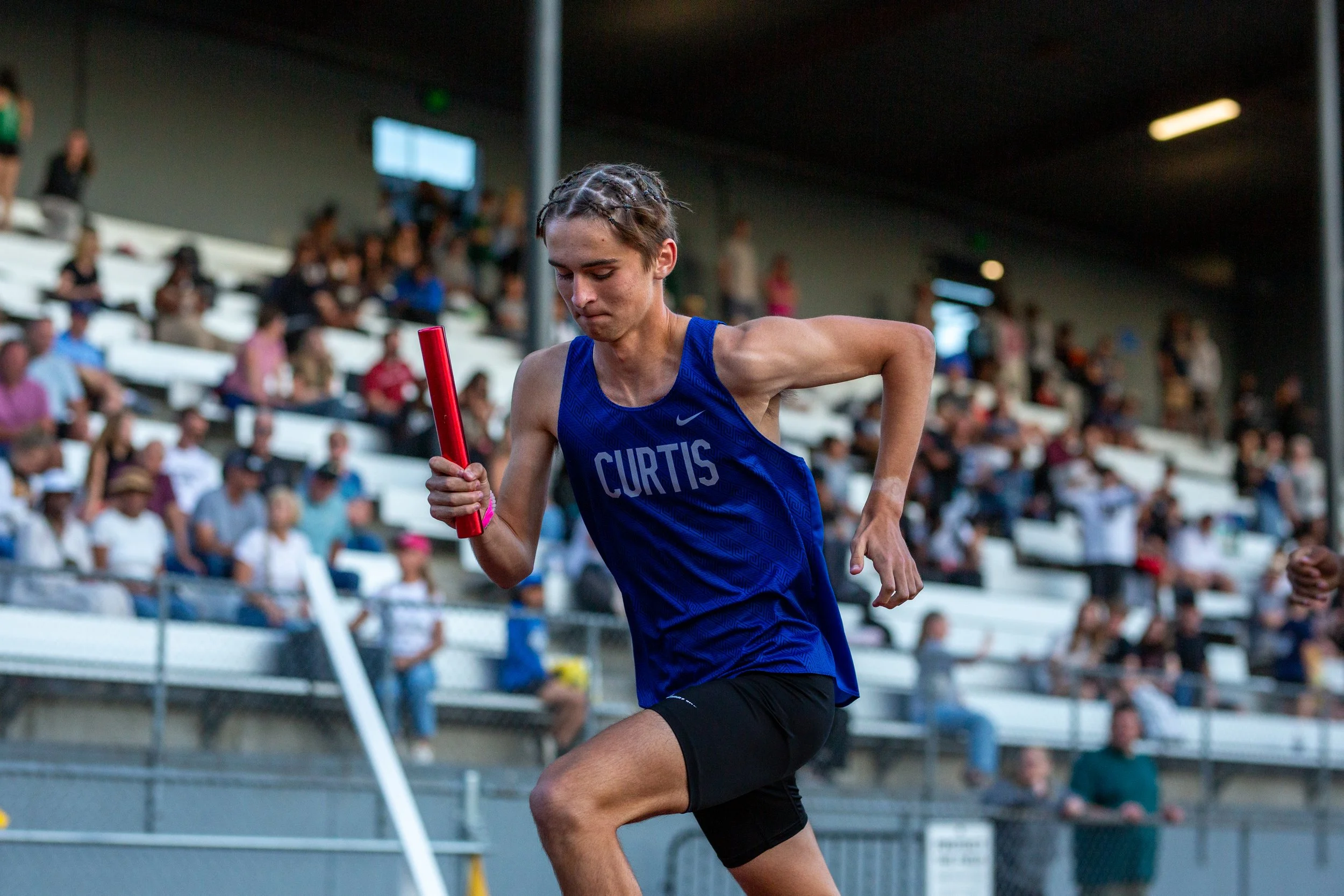 Asher Pepin of Curtis High School carrying the baton during a relay race at the 2026 District track and field championships.