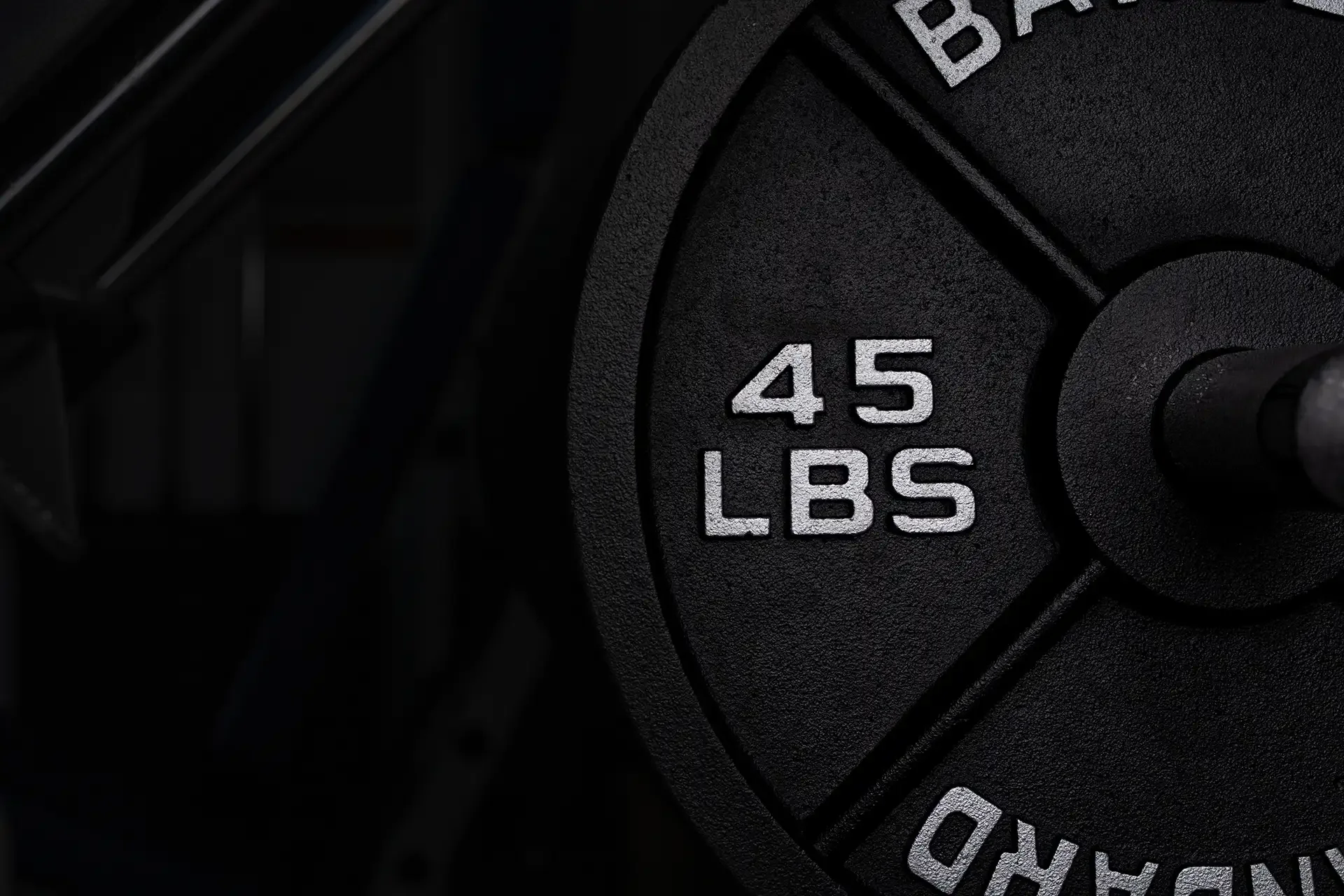 Close-up detail shot of a 45lb barbell plate with chalk dust and gym texture. Gritty, high-contrast black and white fitness branding photography for local gyms in Olympia, WA