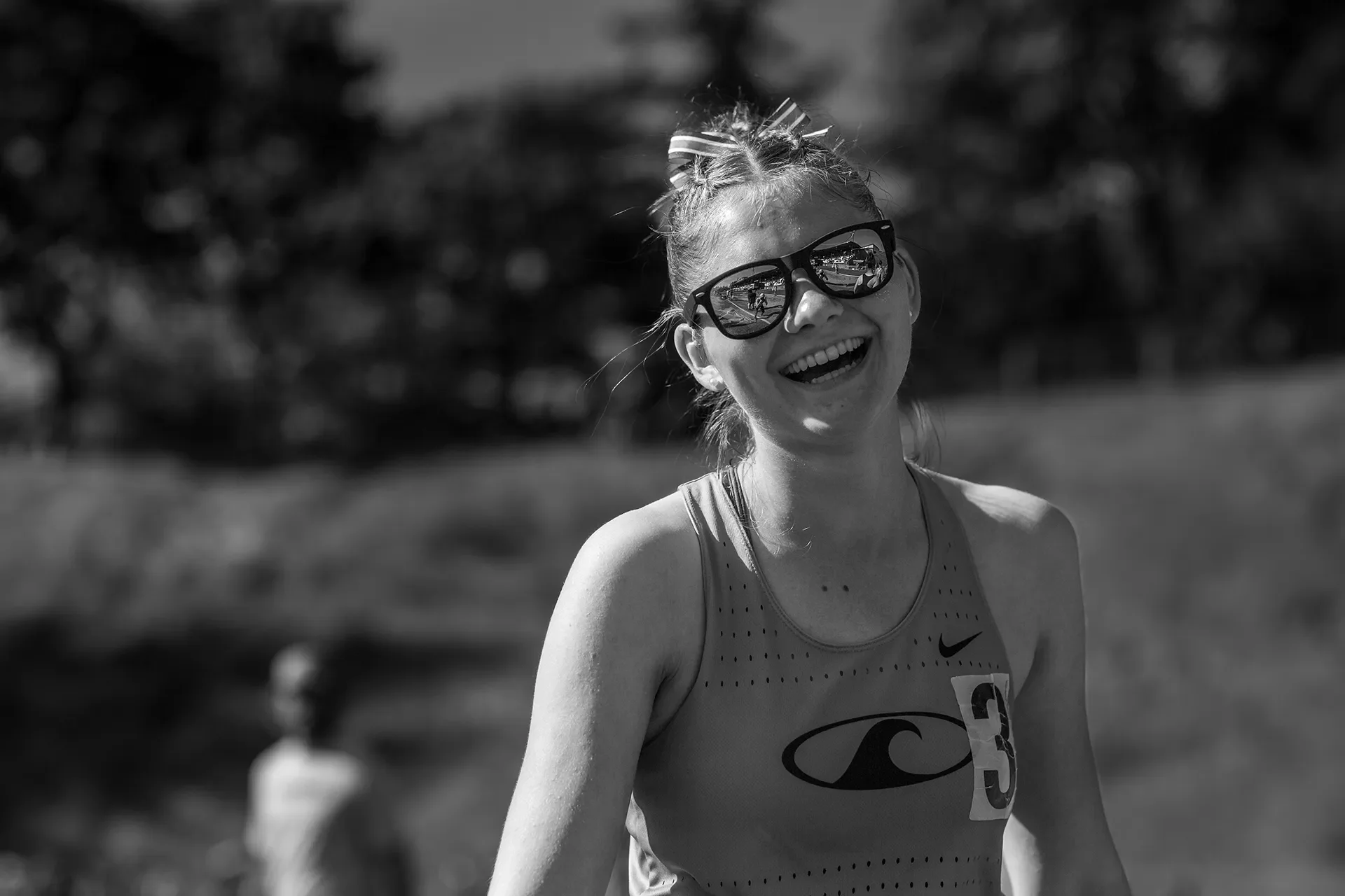 A female athlete from Gig Harbor High School with a number three pinned to her jersey smiles for a photo.