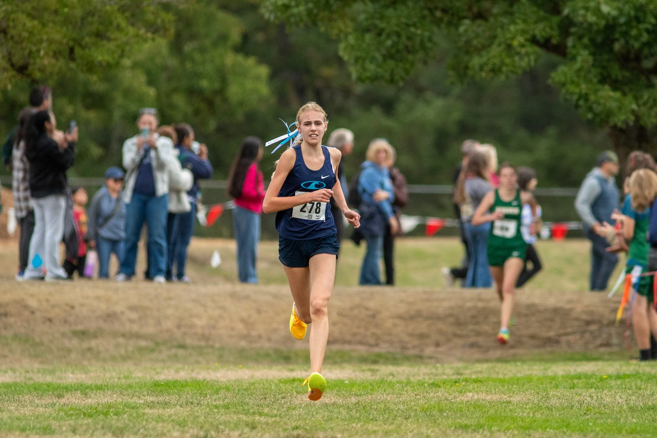 High school girl in a Gig Harbor singlet running with a pack of runners.