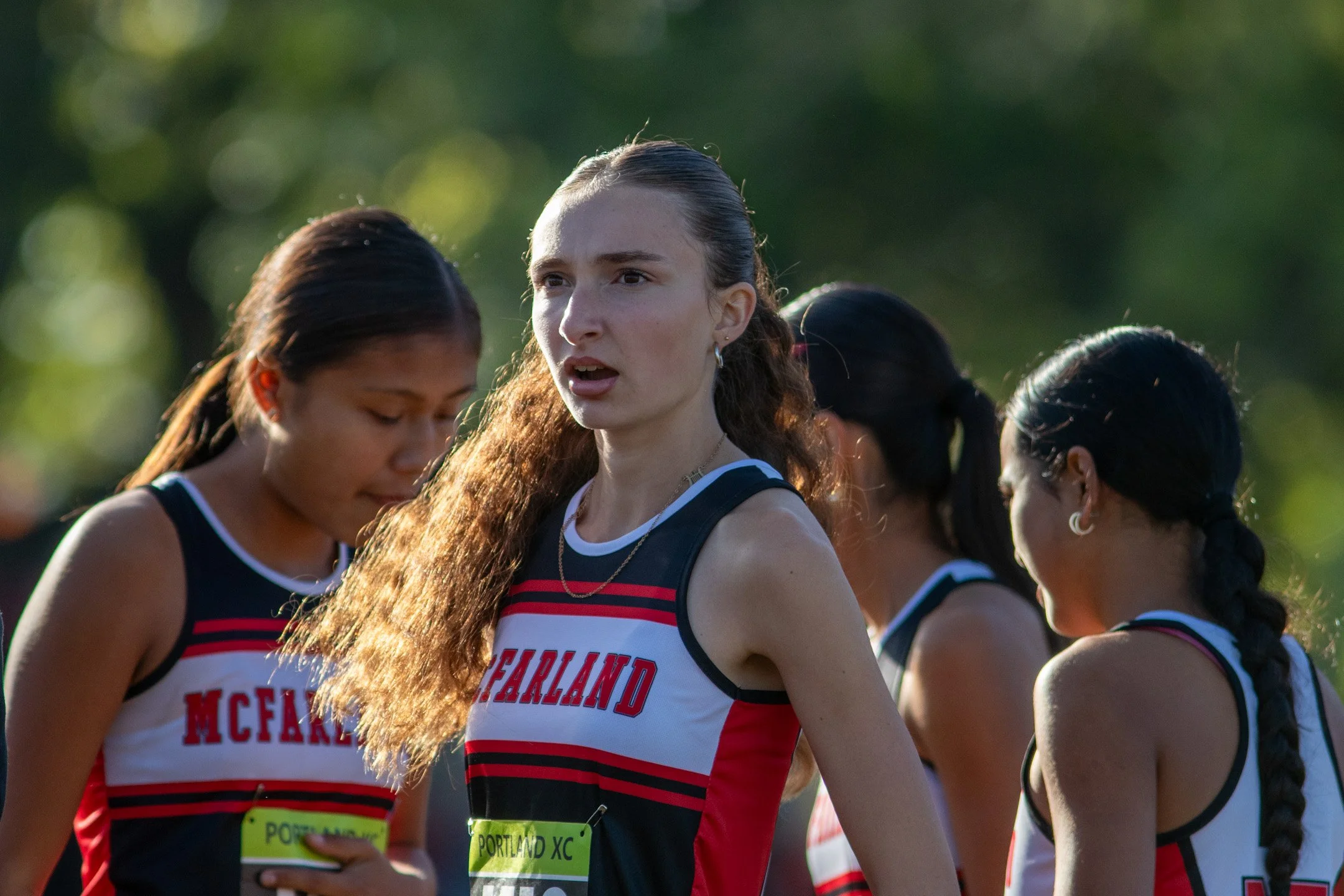 McFarland sophomore Jennifer Diaz in sharp focus, hair catching the sun, stands with two teammates before the start.