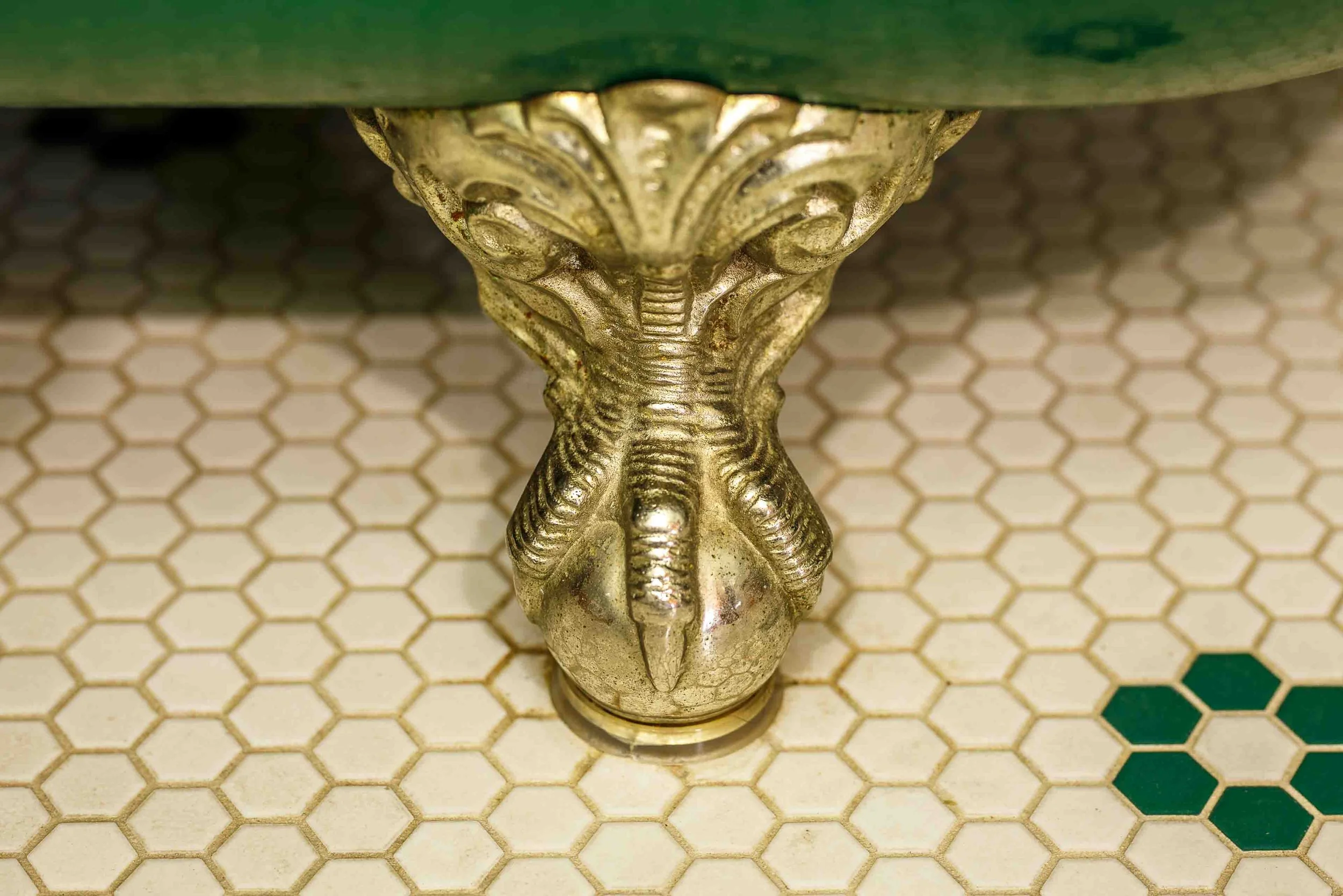 Detail shot of an antique brass elephant-head door pull on hexagonal tile flooring at Swantown Inn