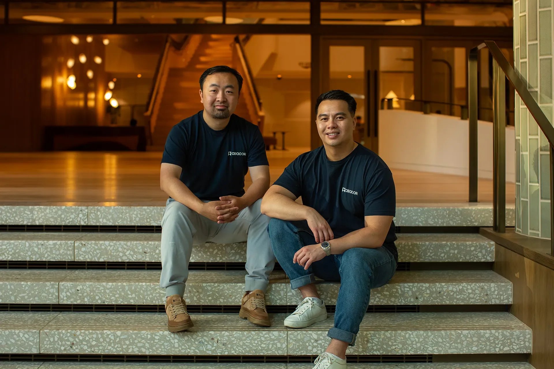 Professional environmental portrait of two team members sitting on office steps, illustrating high-quality on-location commercial photography.