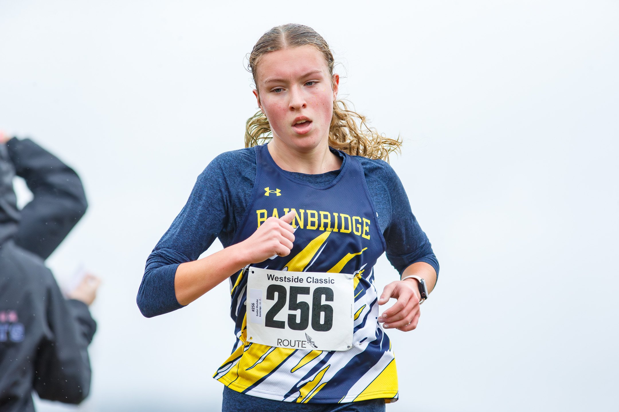 Bainbridge's Evelyn Shutske running in a navy and gold uniform