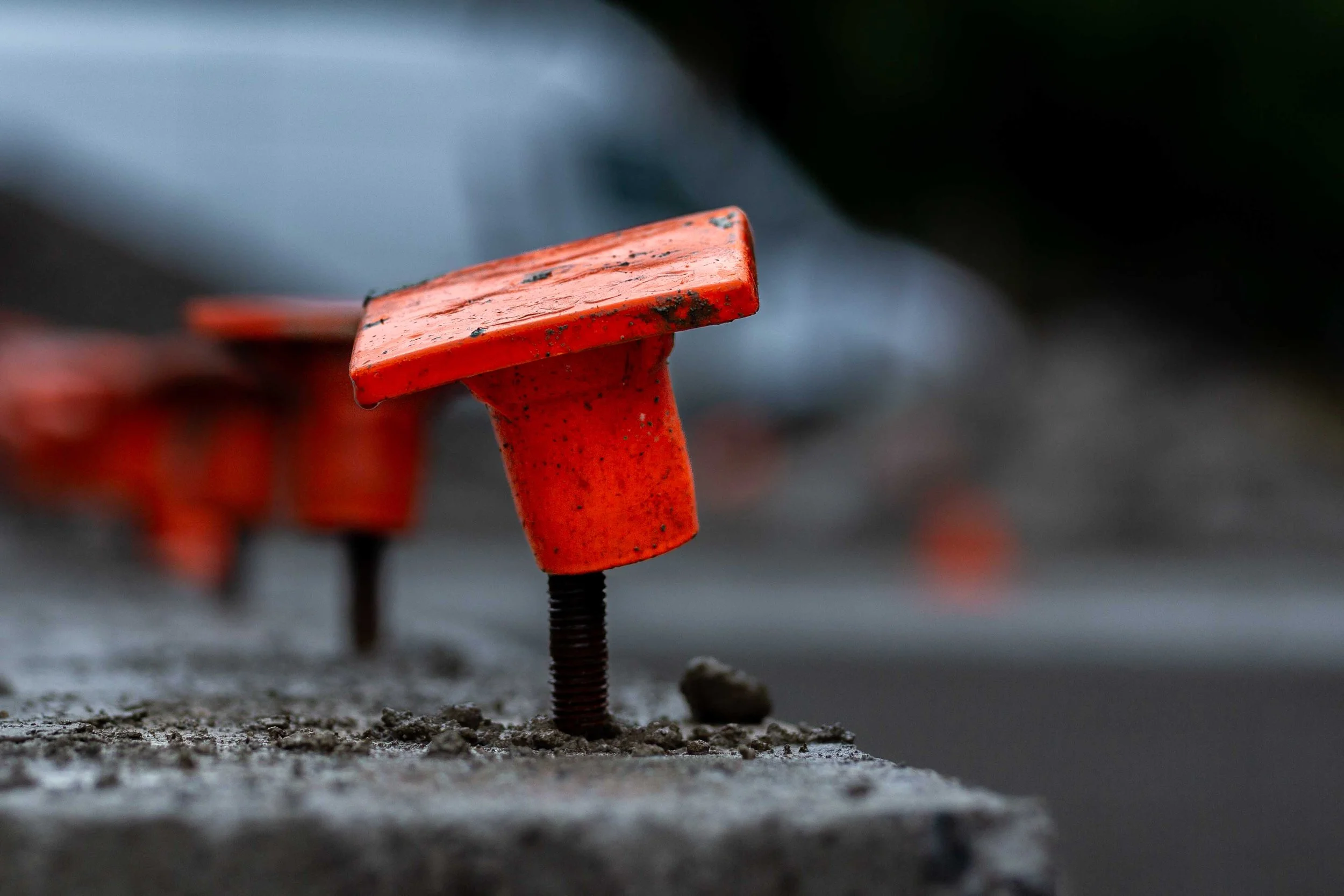 Close-up of bright orange rebar safety caps on an active commercial construction site in Olympia, Washington, illustrating the physical hazards and liability considerations required during on-location architectural photography.