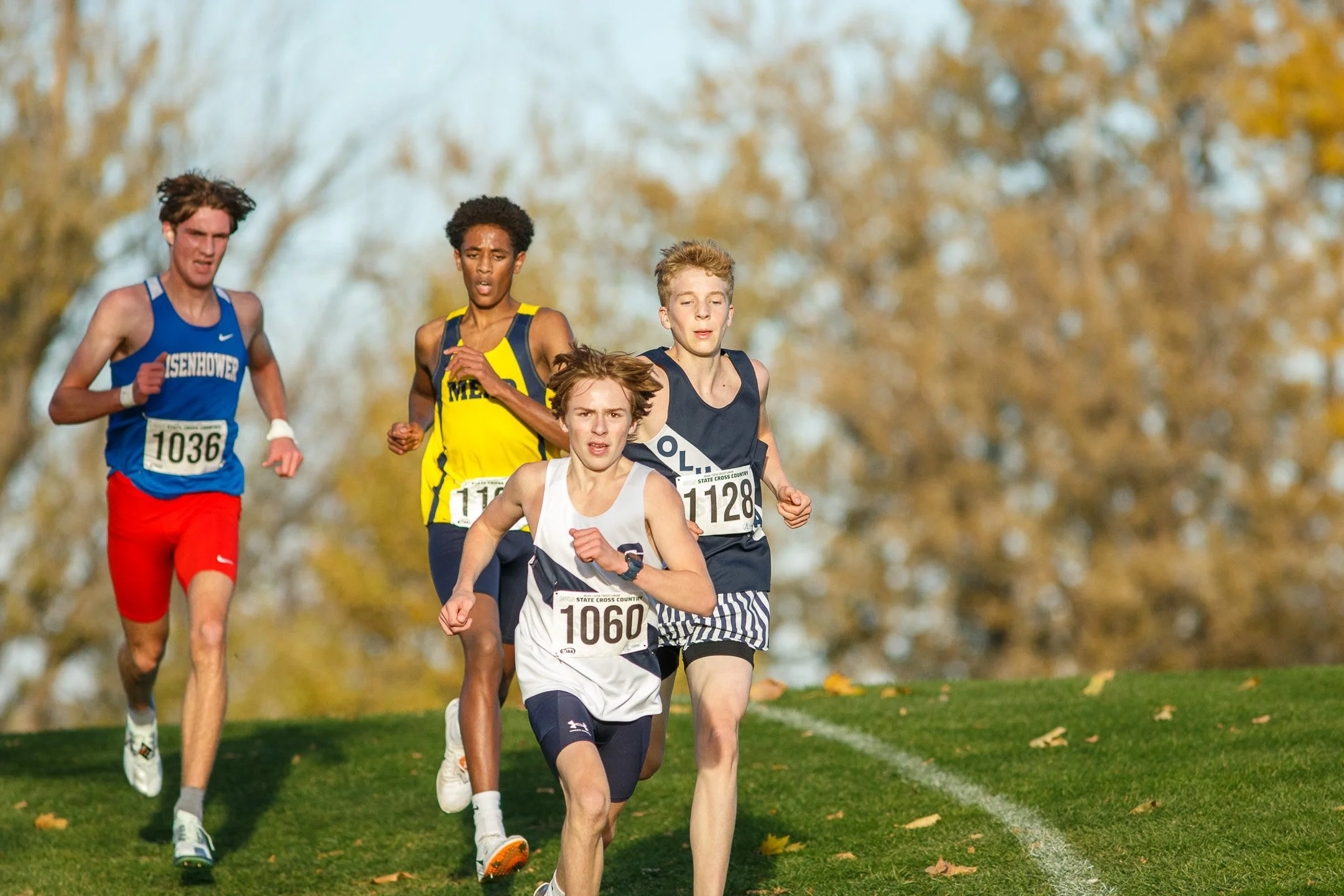 A tight pack of four high school cross country runners competing during the state championships.