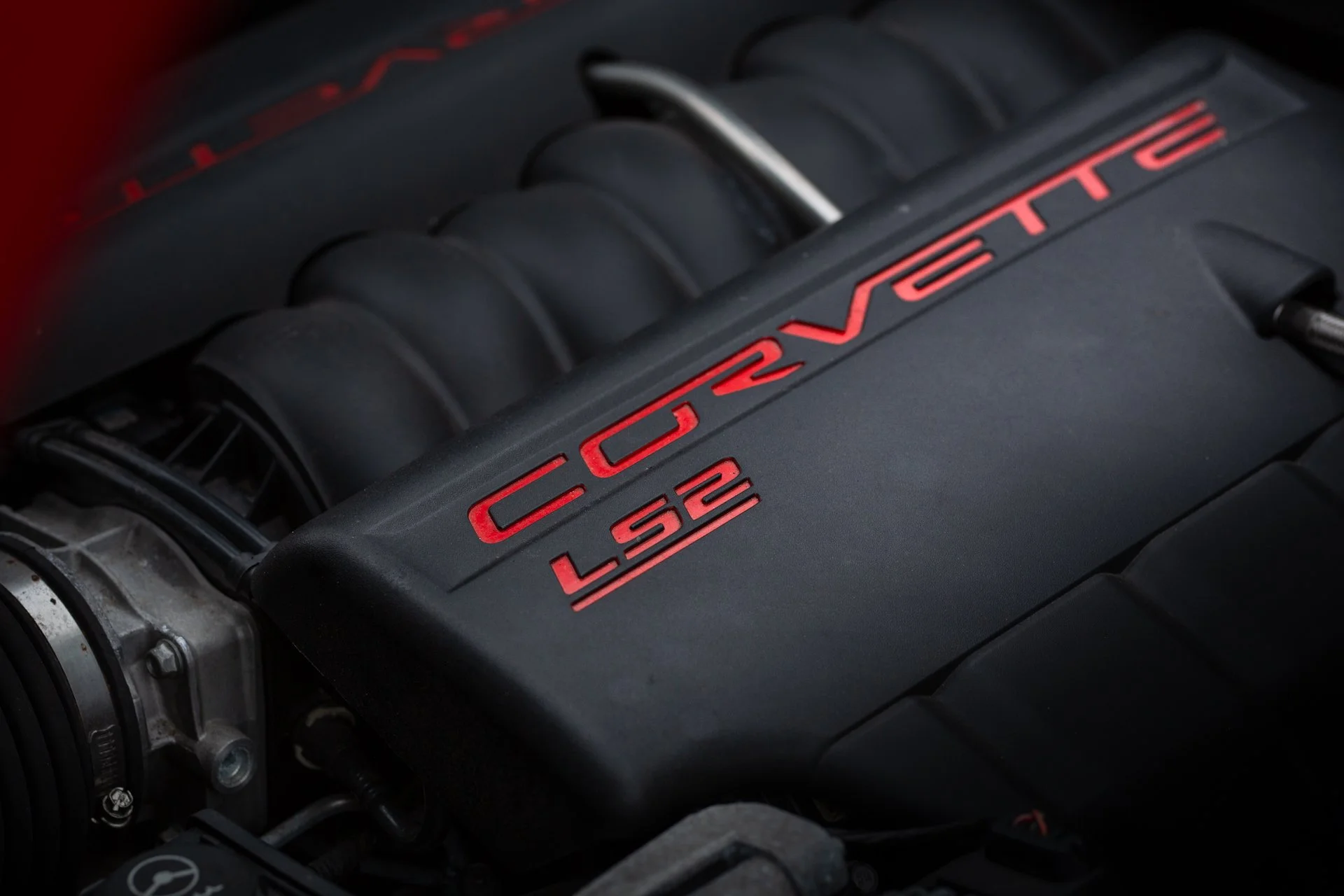 Engine LS2 of a red 2005 Chevrolet Corvette C6 coupe parked on a street, showcasing its classic sports car design.