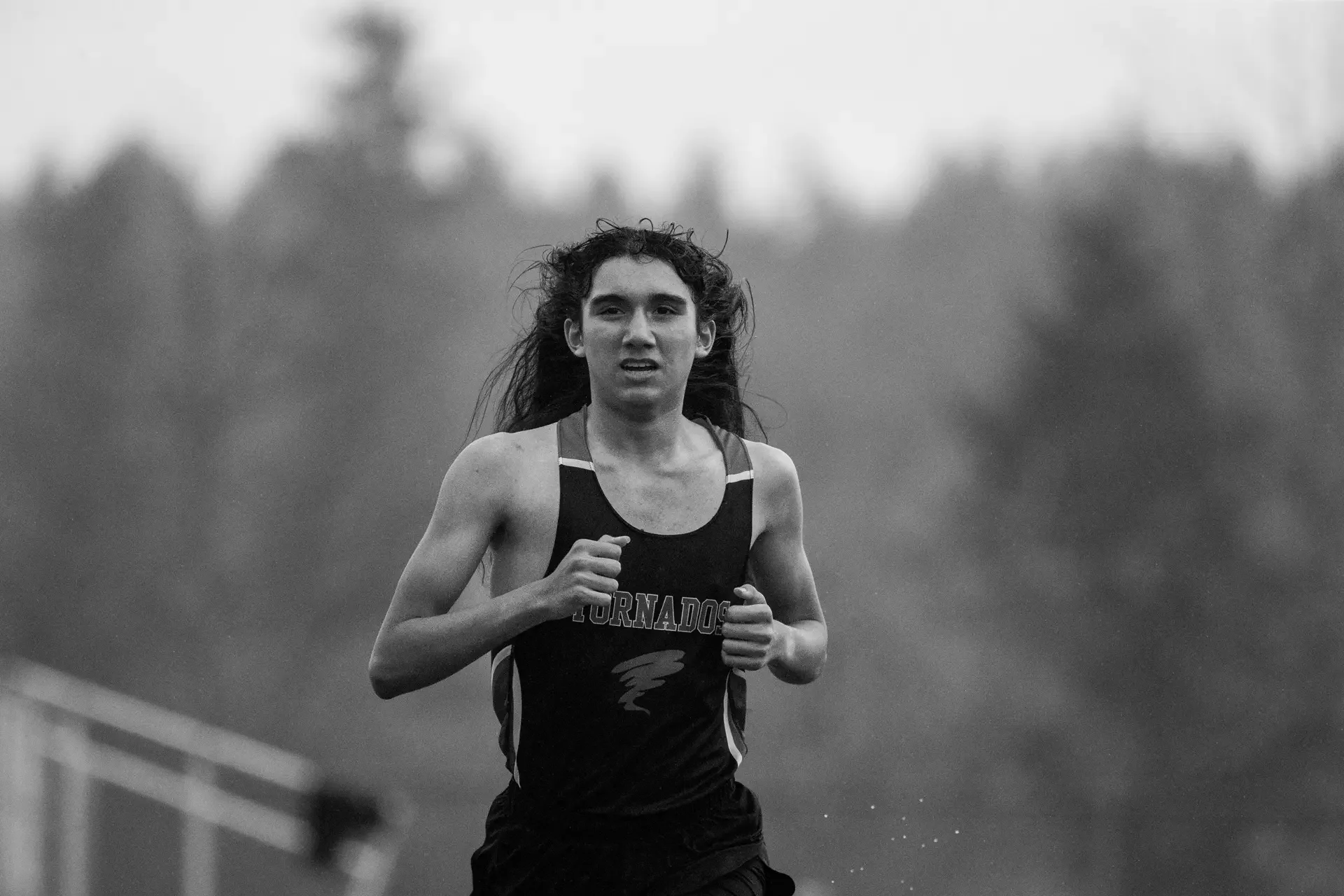 A black and white action shot of track athlete Alejandro Silva running a race at Yelm High School, photographed by Russell Moore.