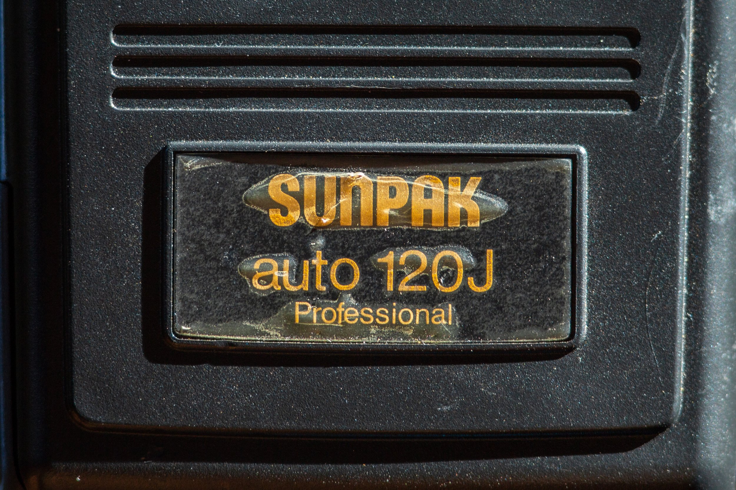 Close-up of the Sunpak Auto 120J Professional nameplate on a vintage flash unit