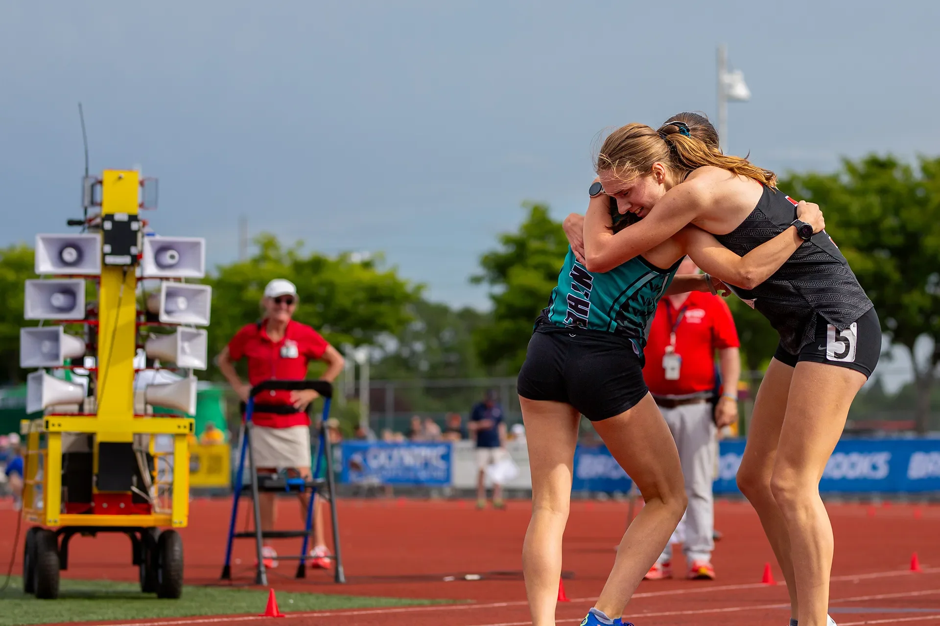 Latham West of Bonney Lake, the 4A girls 1600M state champion, hugs Union High School runner Ella Koch on the track.