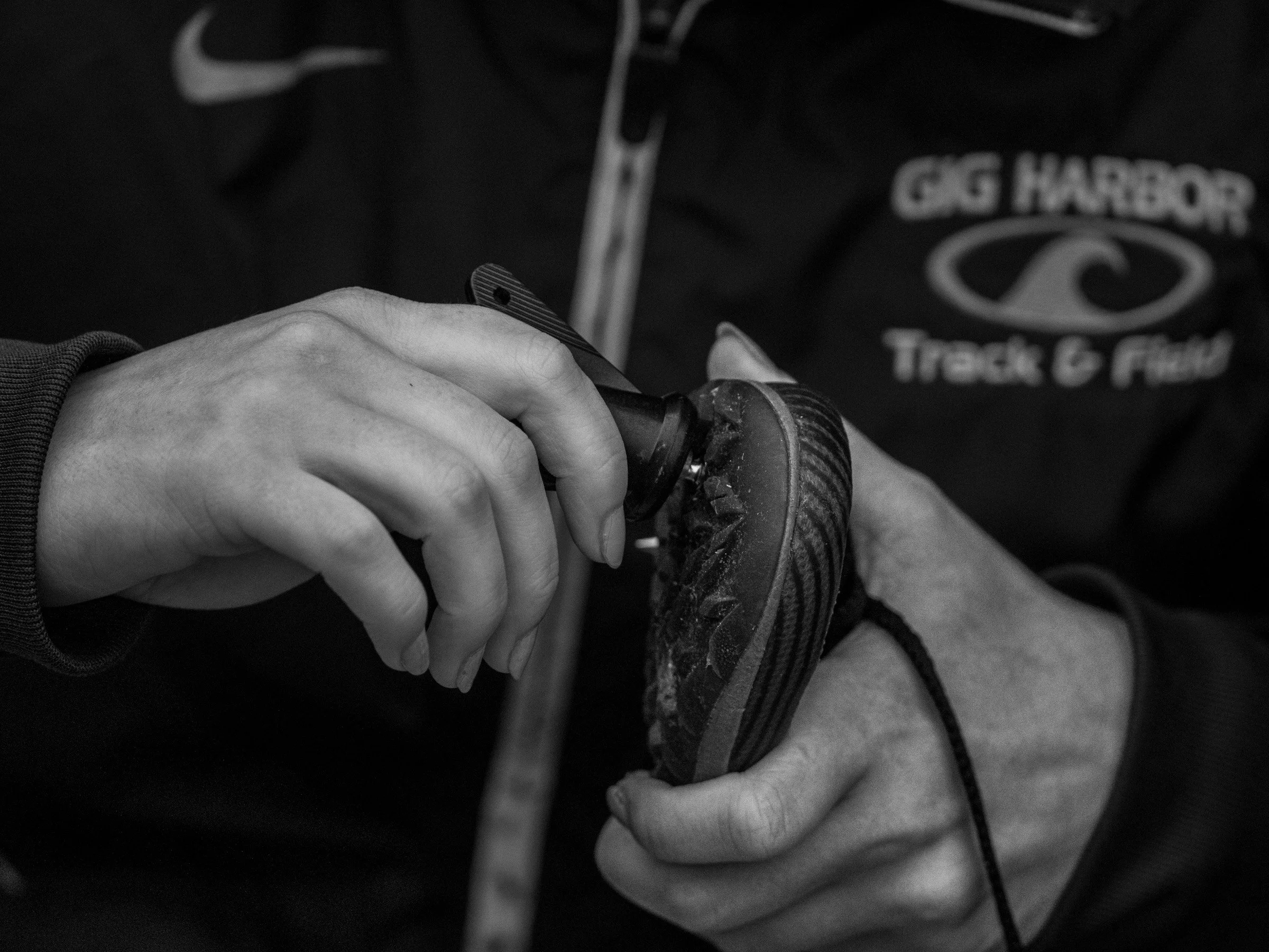 Close-up of a runner’s hands gripping a well-worn racing spike with a cracked sole.