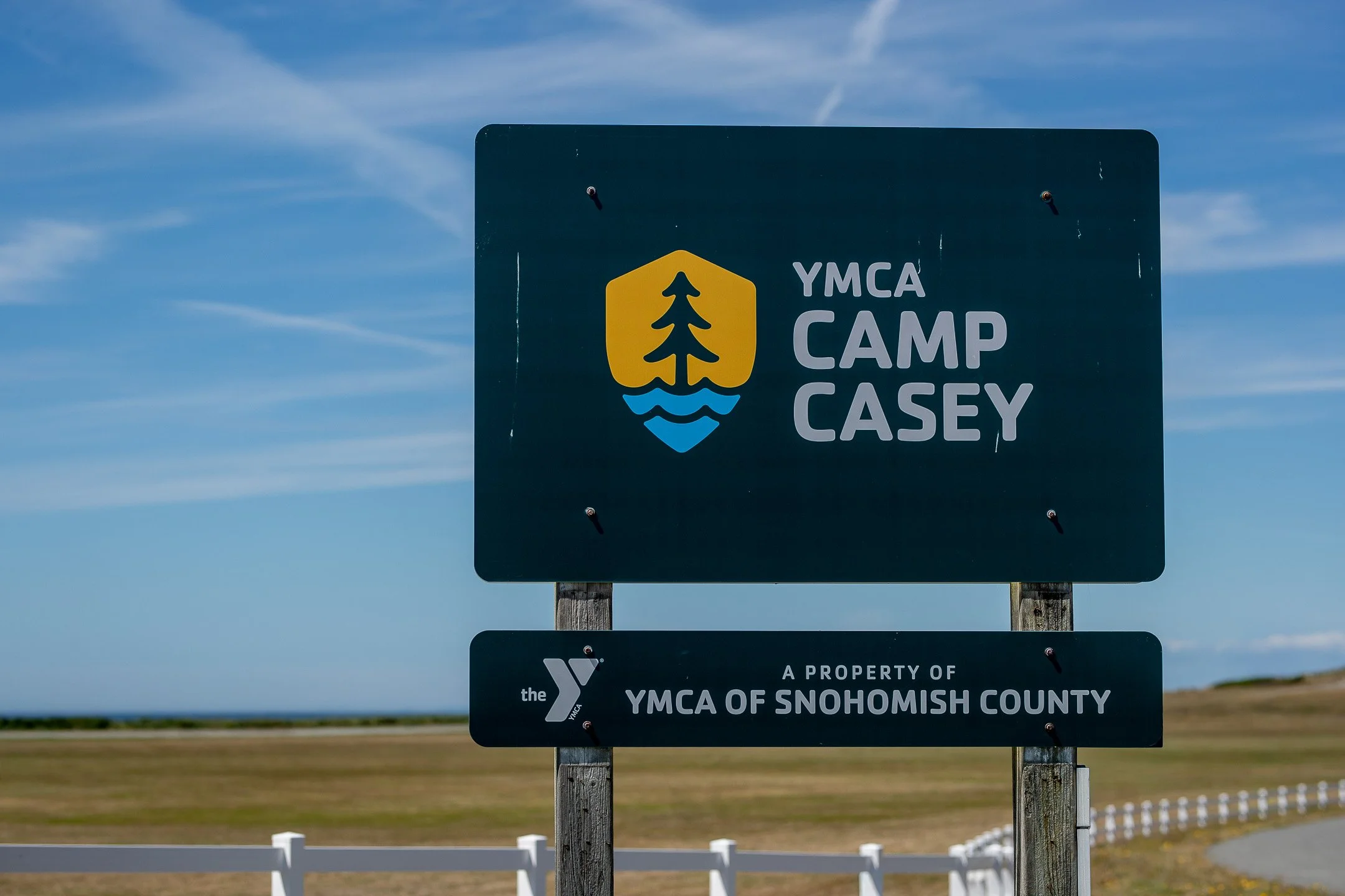 The wooden entrance sign for Camp Casey Conference Center surrounded by coastal vegetation in Coupeville, Whidbey Island.