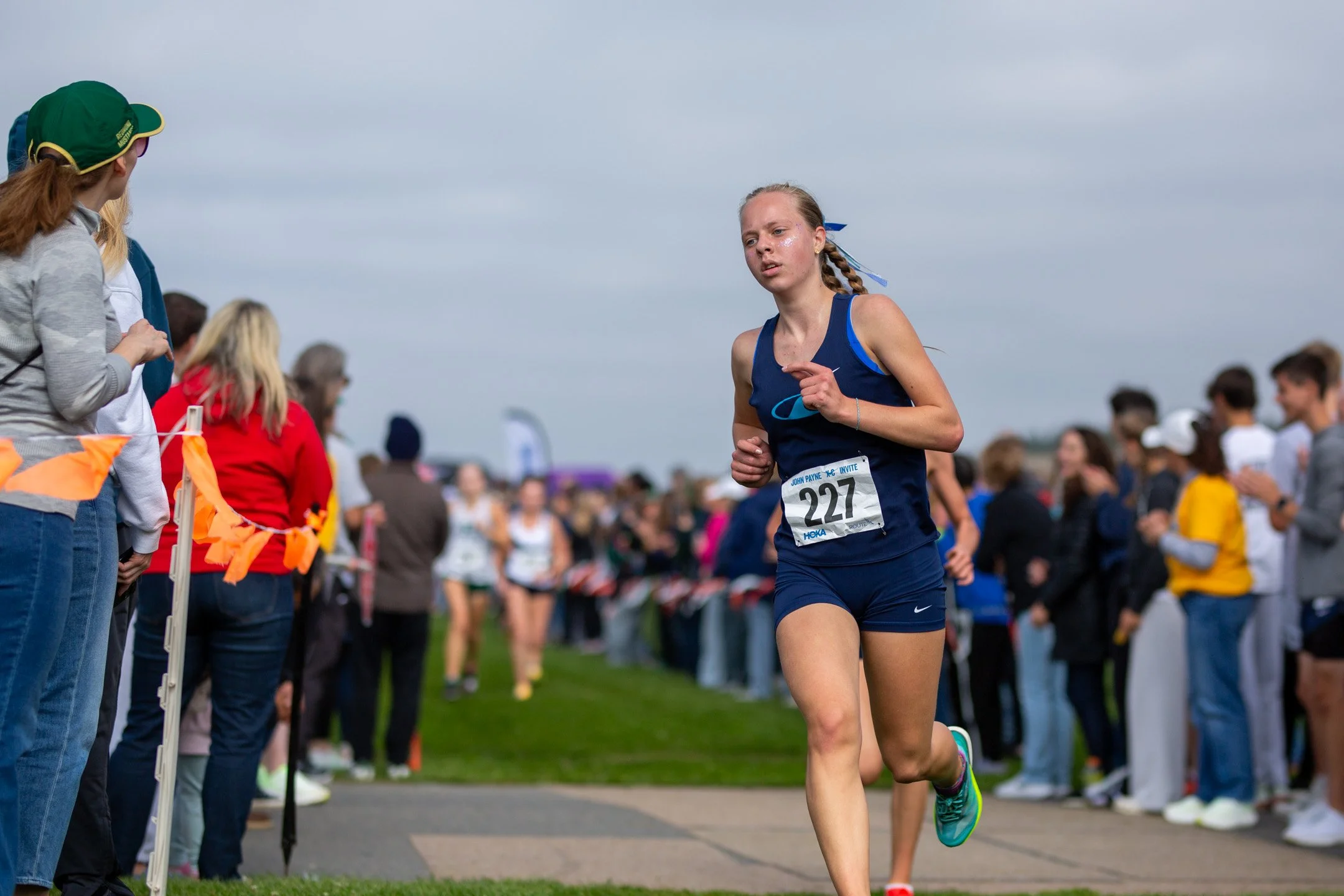 Gig Harbor sophomore Brynnlie Upchurch, bib 227, in a navy Gig Harbor singlet, running past spectators lining the course.