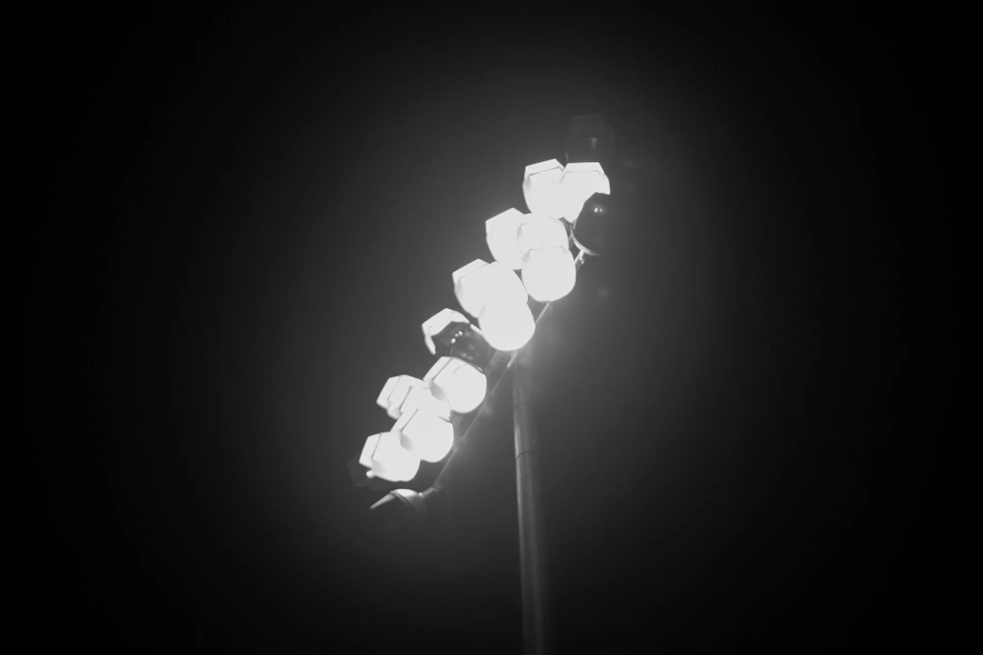Black and white photo of stadium floodlights against a dark night sky, symbolizing the goal of winter track training.