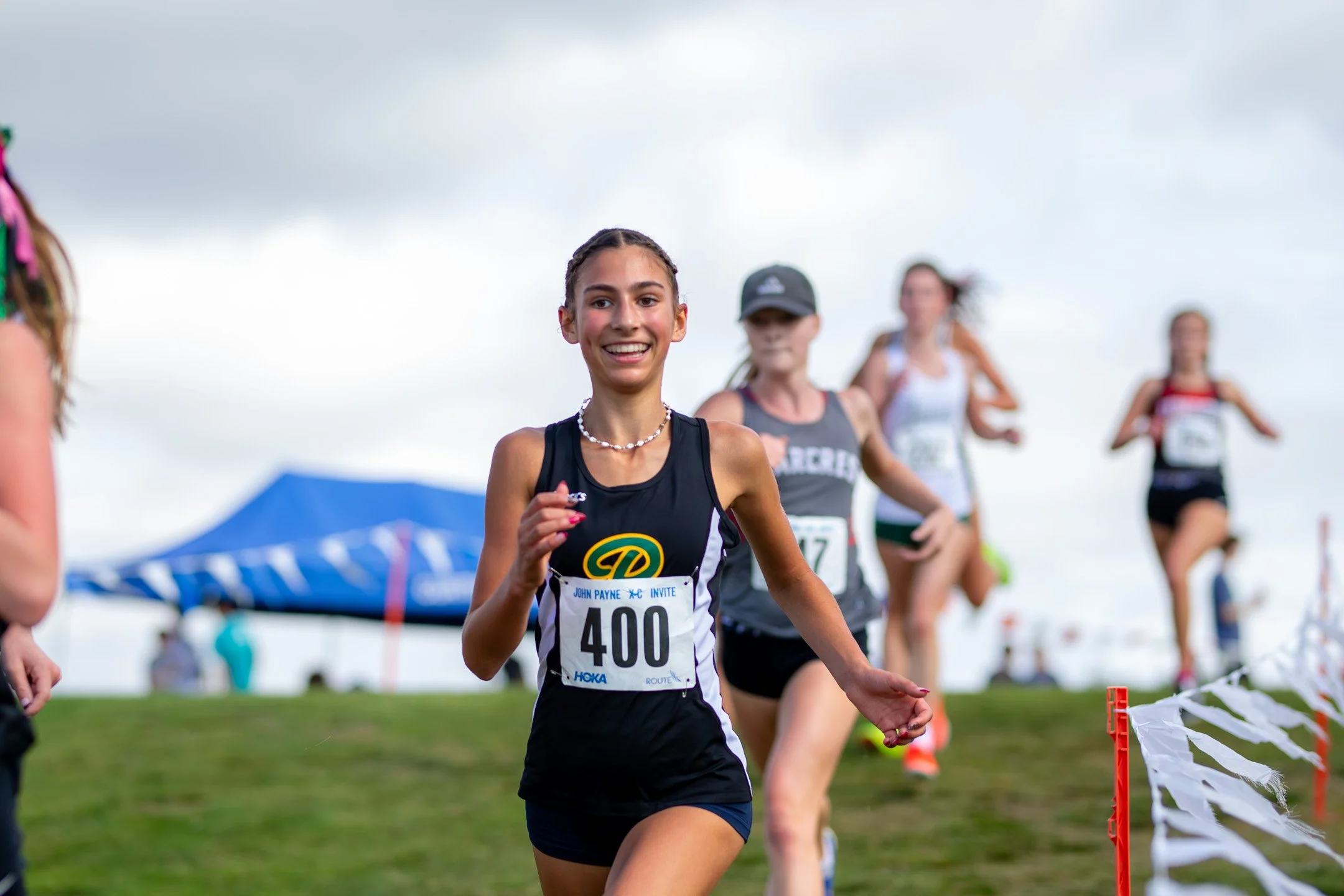 High school girl in a Roosevelt singlet, bib 400, running near the front of a pack.