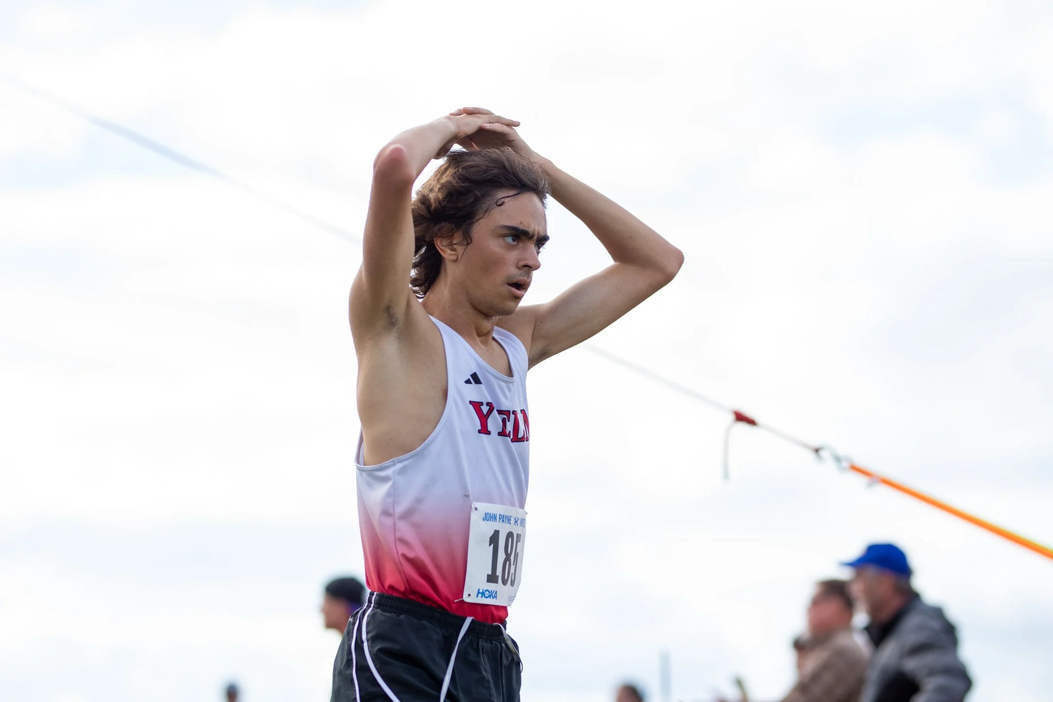 High school boy in a red Yelm singlet competing with another runner.
